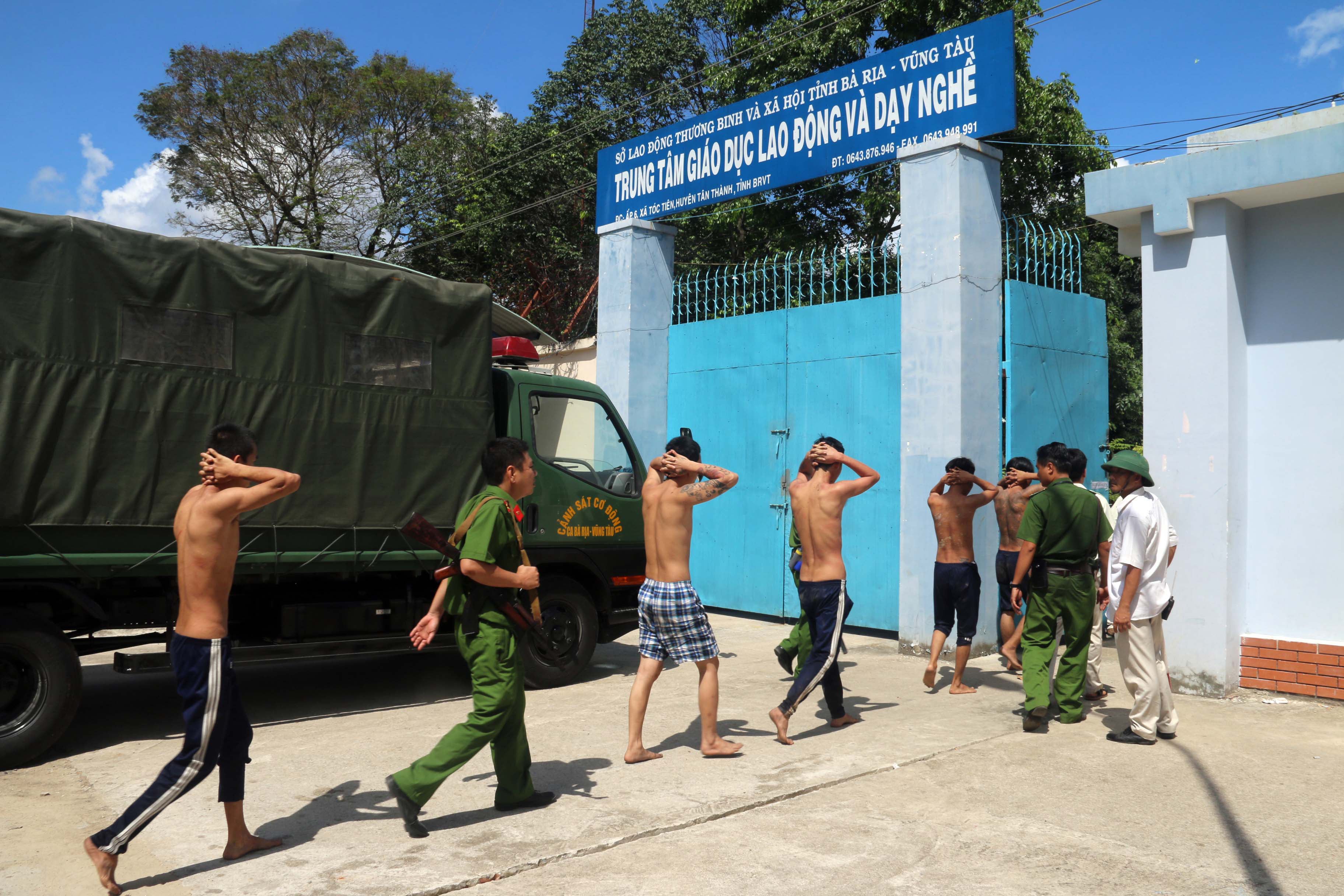 This picture taken on 9 November 2016 shows recaptured inmates, who escaped from a drug rehabilitation centre, being escorted by police back to their rehab centre in the in the southern province of Ba Ria-Vung Tau following a mass breakout