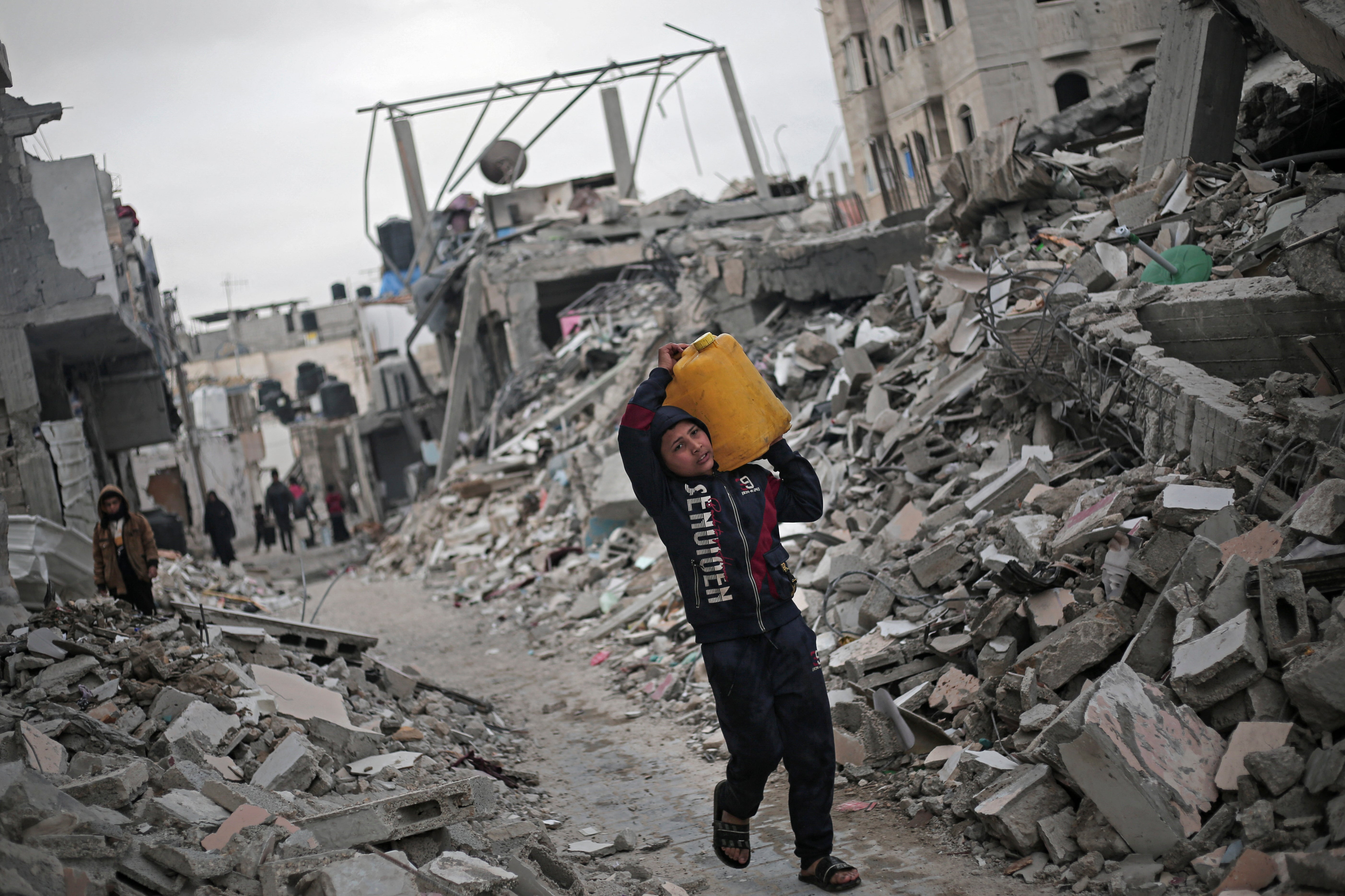 A Palestinian boy carries a water container amid the rubble of houses destroyed by Israeli bombardment in Rafah