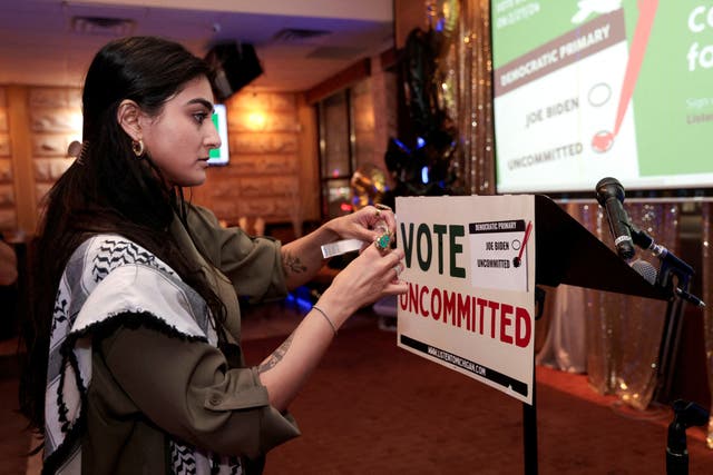 Activist Natalia Latif tapes a Vote Uncommitted sign on the speaker's podium during an uncommitted vote election night gathering as Democrats and Republicans hold their Michigan primary presidential election, in Dearborn, Michigan, U.S., February 27, 2024