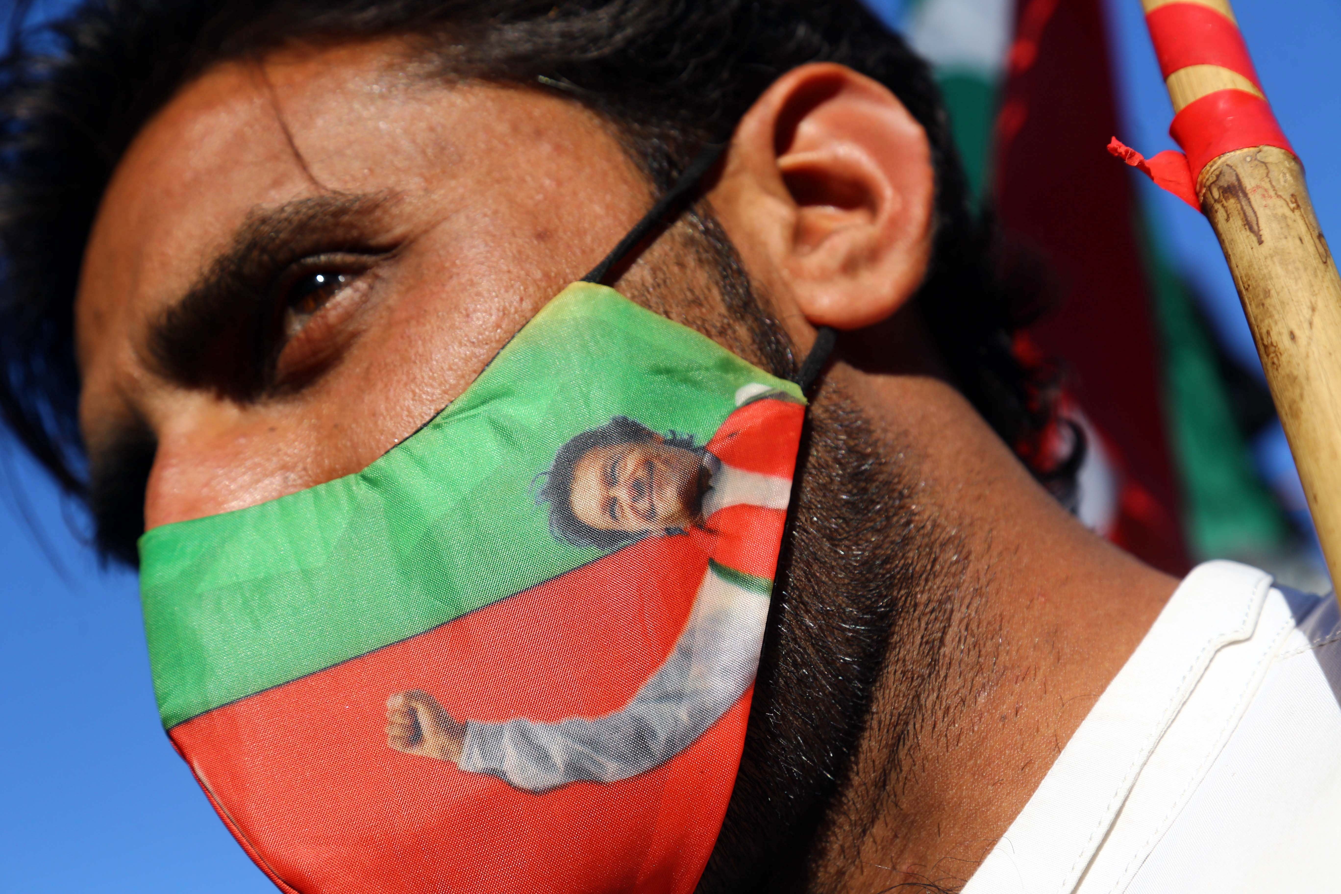 A supporter of the Pakistan Tehrik-e-Insaf (PTI) political party wears a facemask with the picture of party leader Imran Khan, during a protest against alleged rigging in the general election