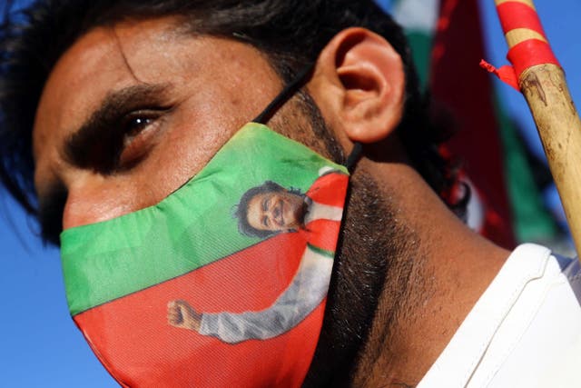 <p>A supporter of the Pakistan Tehrik-e-Insaf (PTI) political party wears a facemask with the picture of party leader Imran Khan, during a protest against alleged rigging in the general election</p>