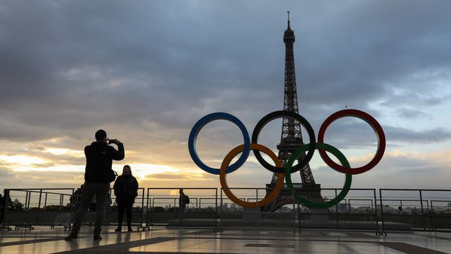 <p>People take photos at sunrise by the Olympic rings installed on the Esplanade du Trocadero near the Eiffel tower </p>