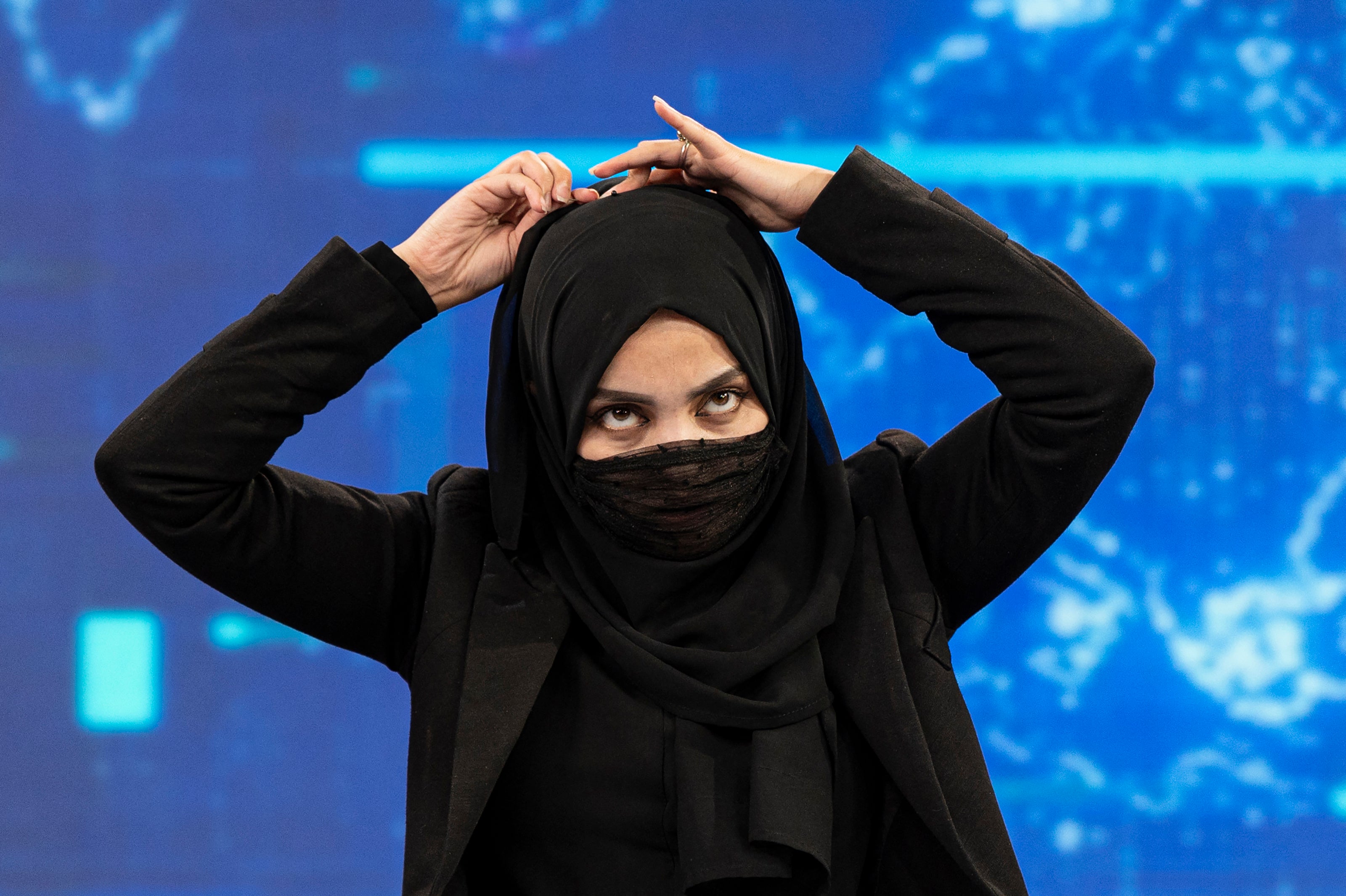 A female presenter for TOLOnews covers her face during a live broadcast at Tolo TV station in Kabul