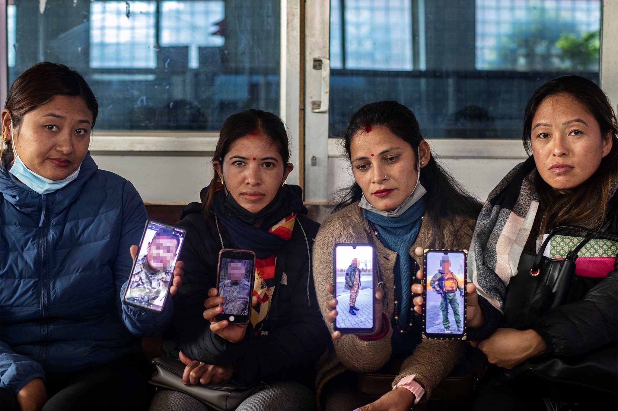 Nepalese wives showing images of their husbands in Russian army uniforms (images blurred upon the wives’ request) in Kathmandu, Nepal