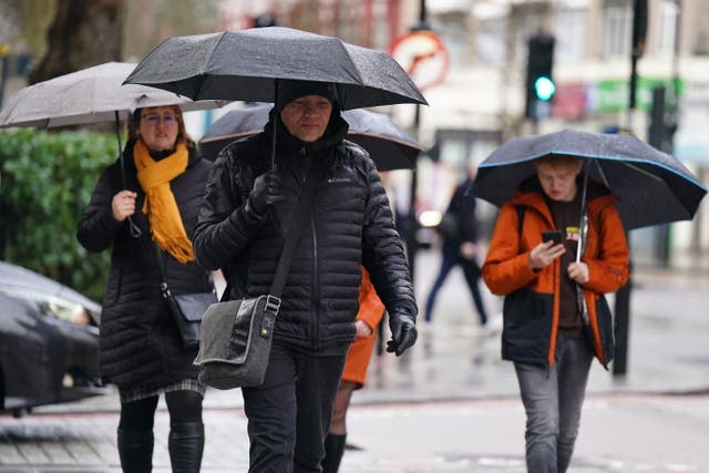 <p>People walk in the rain in central London</p>
