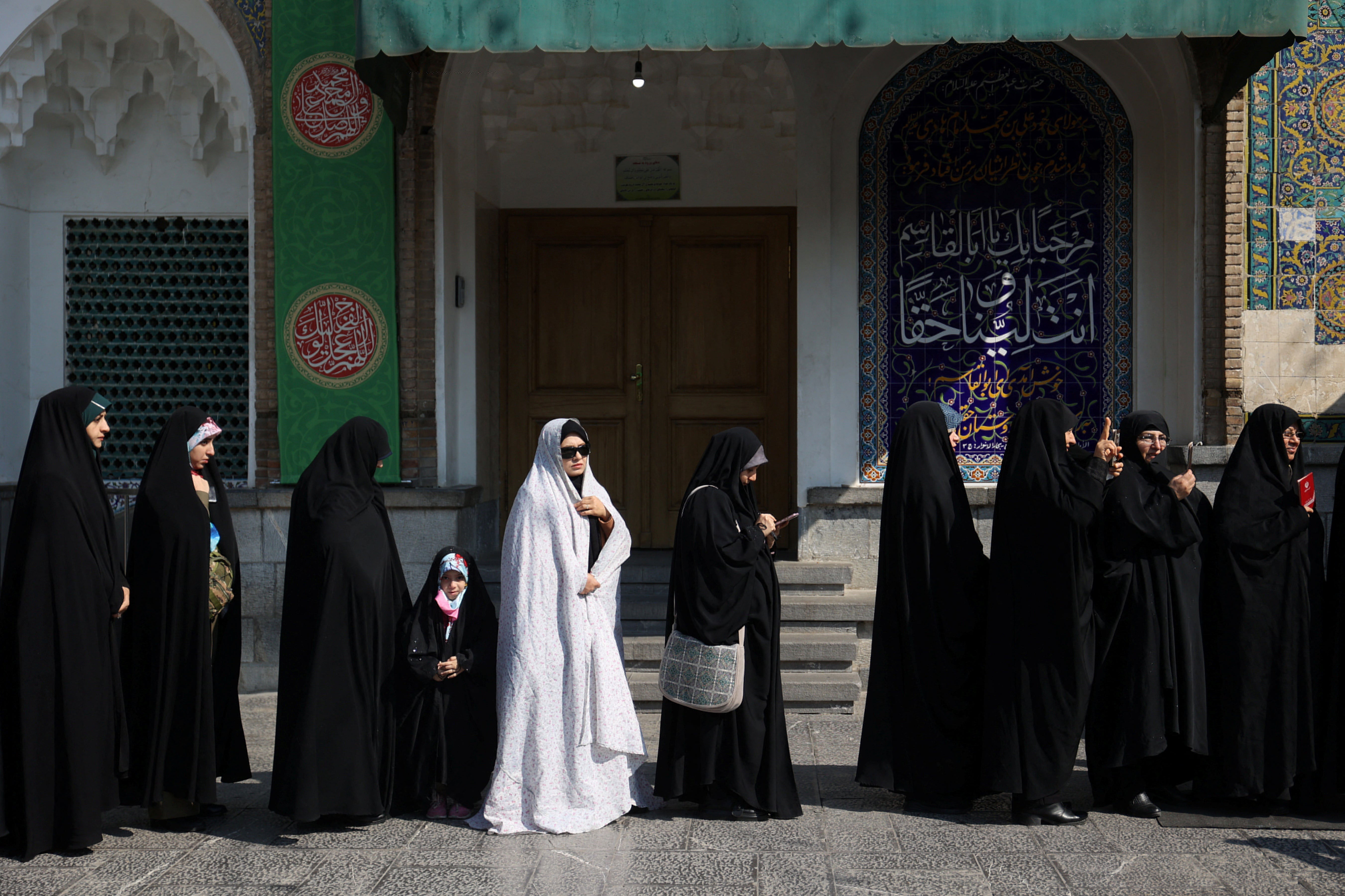 Iranians wait in line to vote at a polling station during parliamentary elections in Tehran