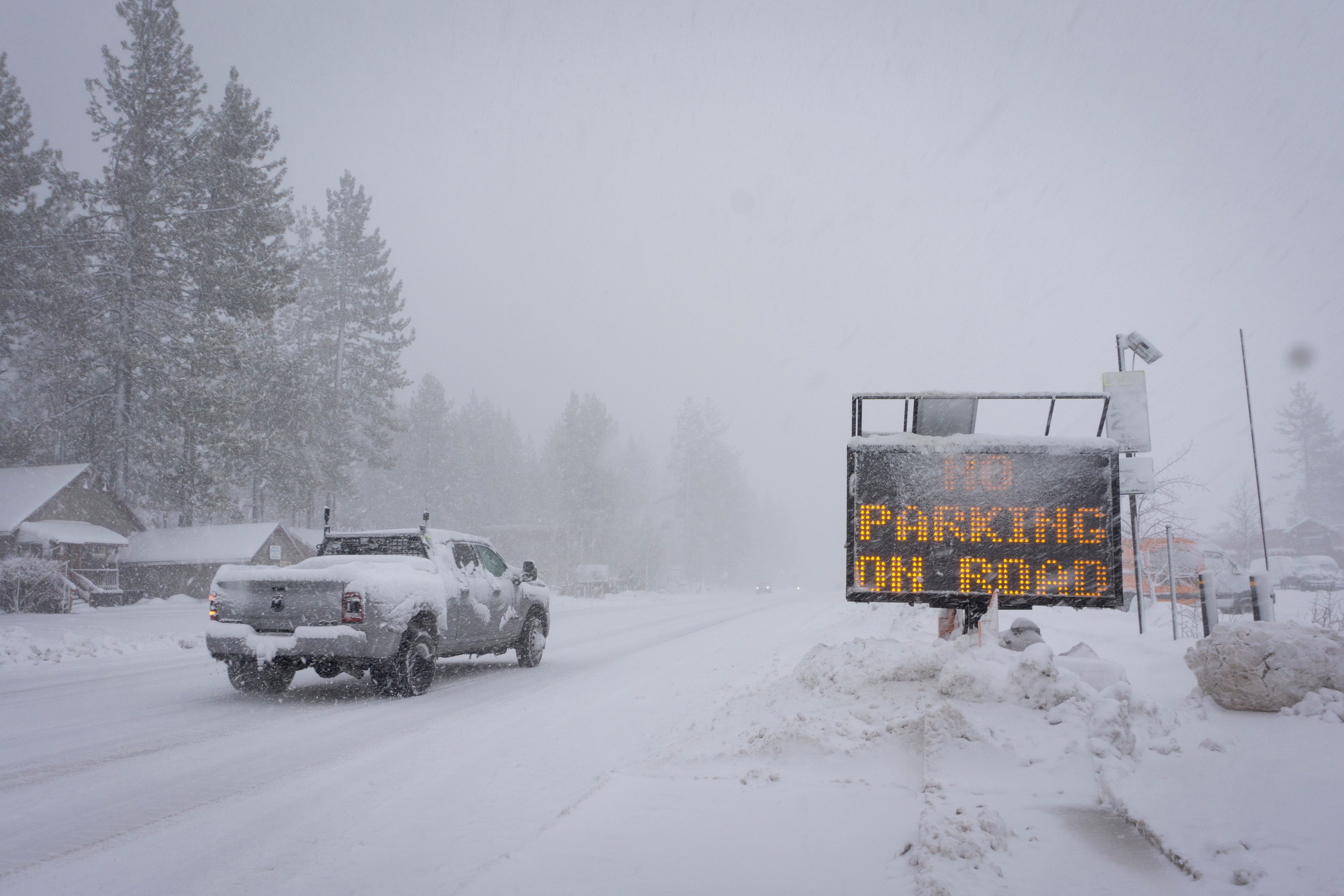 A sign warms motorists of parking restrictions as snow falls Friday, March 1