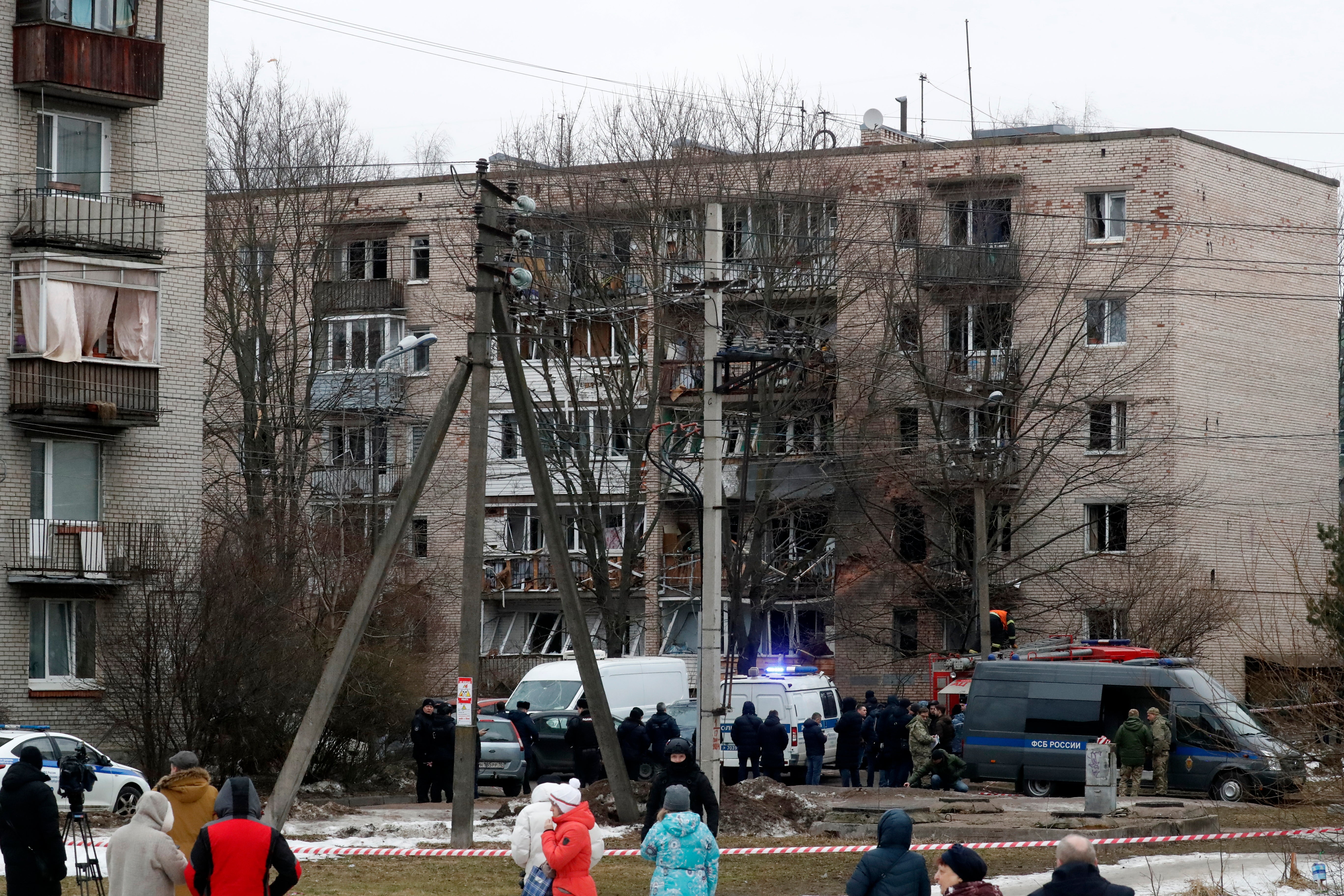 Russian emergency servicemen and investigators work near a damaged multi-storey residential building