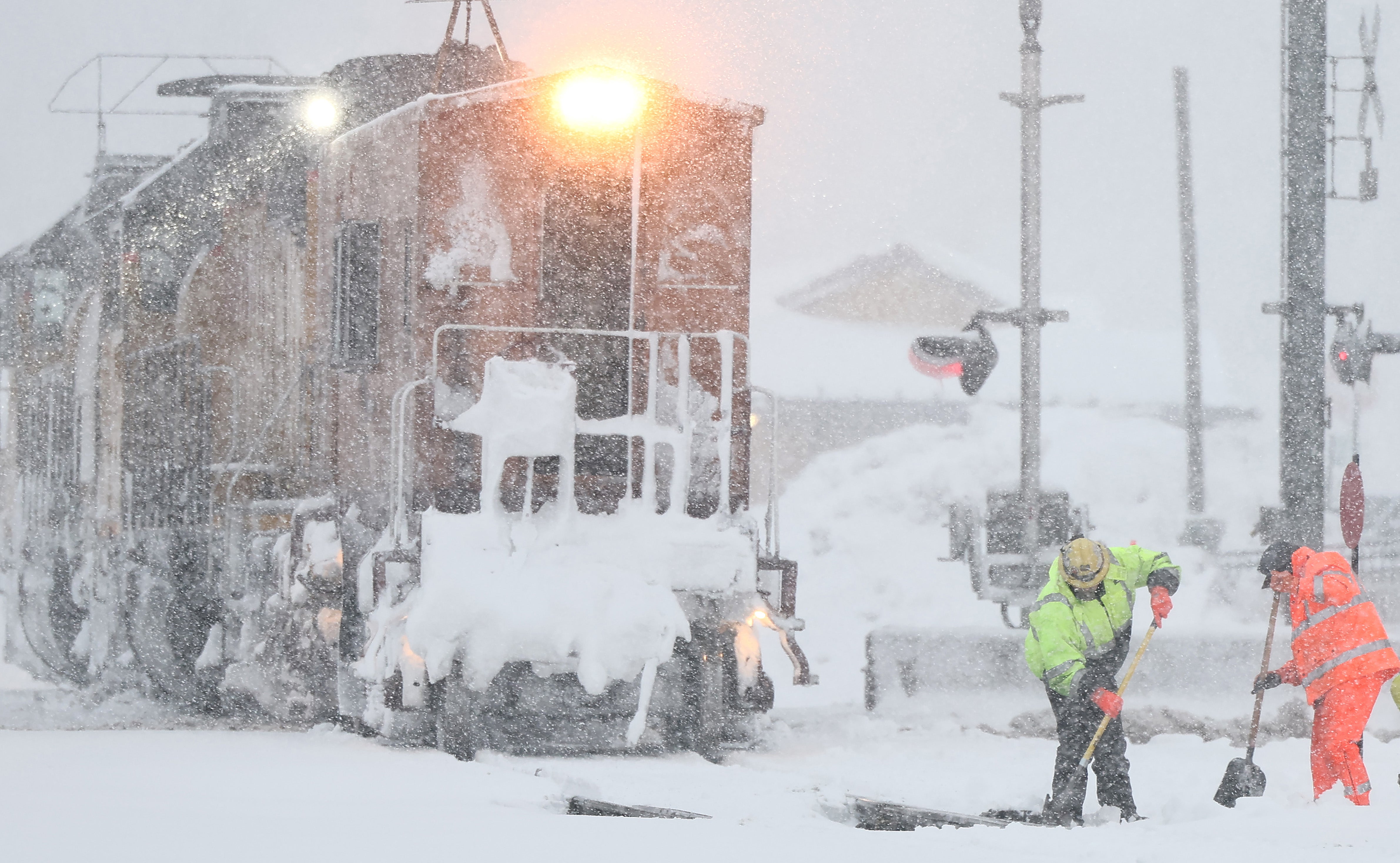 Workers clear train tracks as snow falls north of Lake Tahoe in the Sierra Nevada mountains during a powerful winter storm on March 01, 2024 in Truckee, California