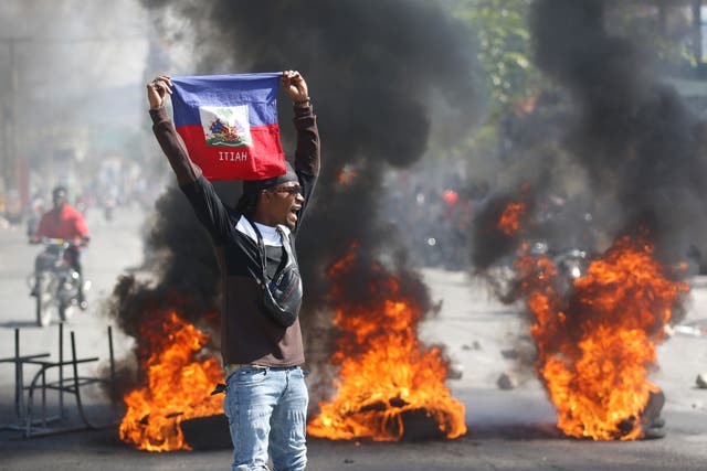 <p>A demonstrator holds up an Haitian flag during protests demanding the resignation of Prime Minister Ariel Henry</p>