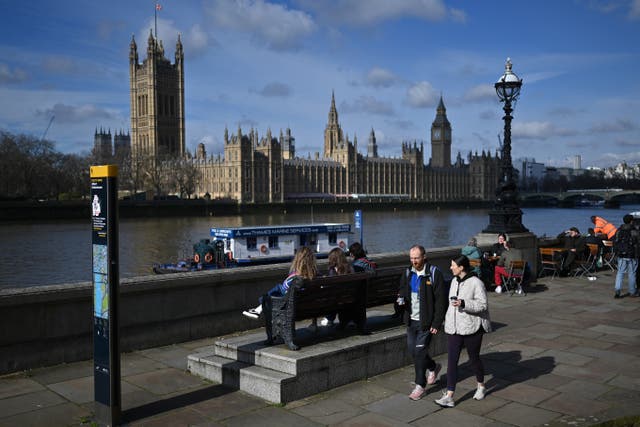 <p>Members of the public walk along the South Bank in the early spring sunshine beside the River Thames</p>