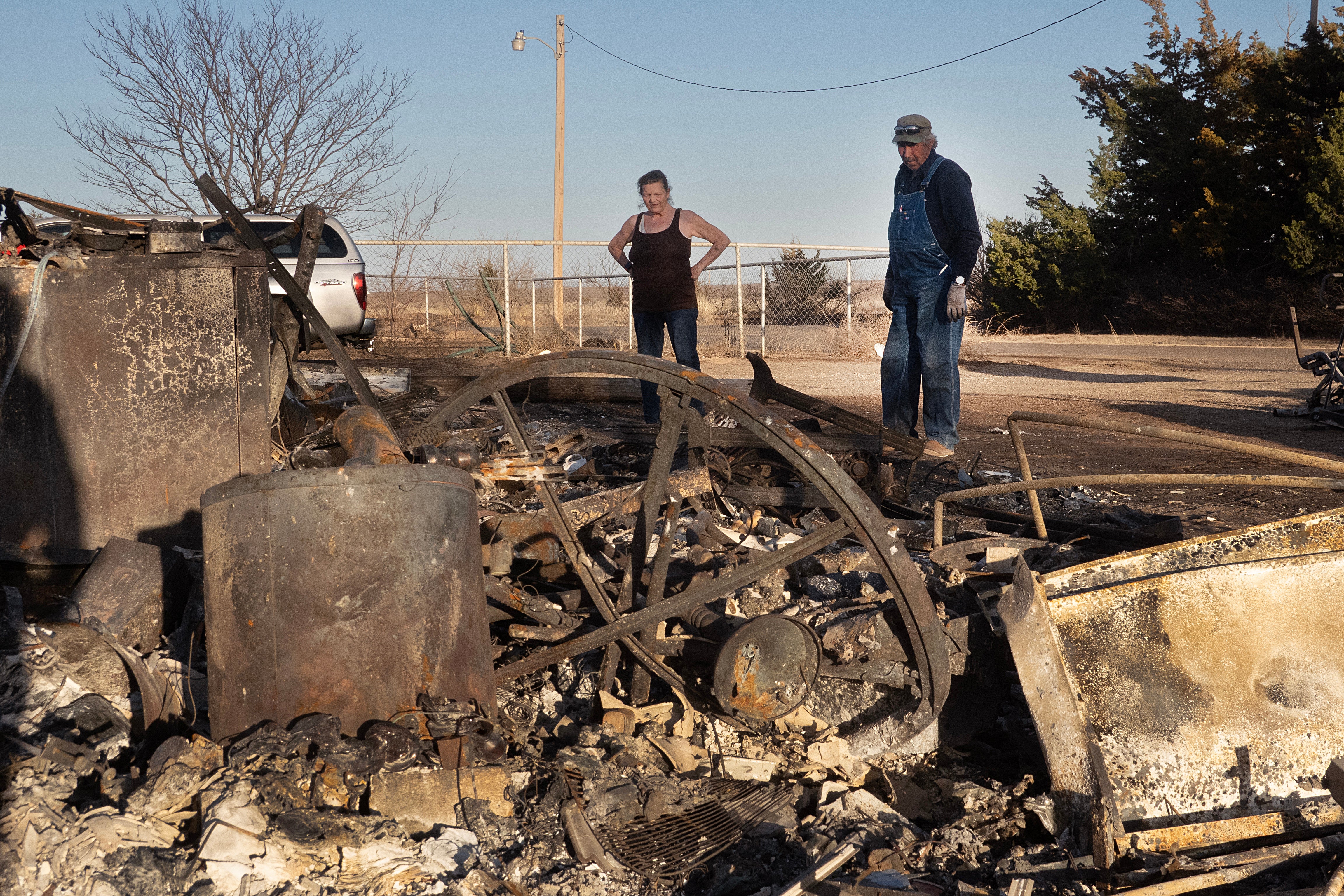 Vernon Jones helps his wife Melissa clean debris from her father's property after a garage and carport were destroyed by the Smokehouse Creek fire on March 03, 2024 near Stinnett, Texas.