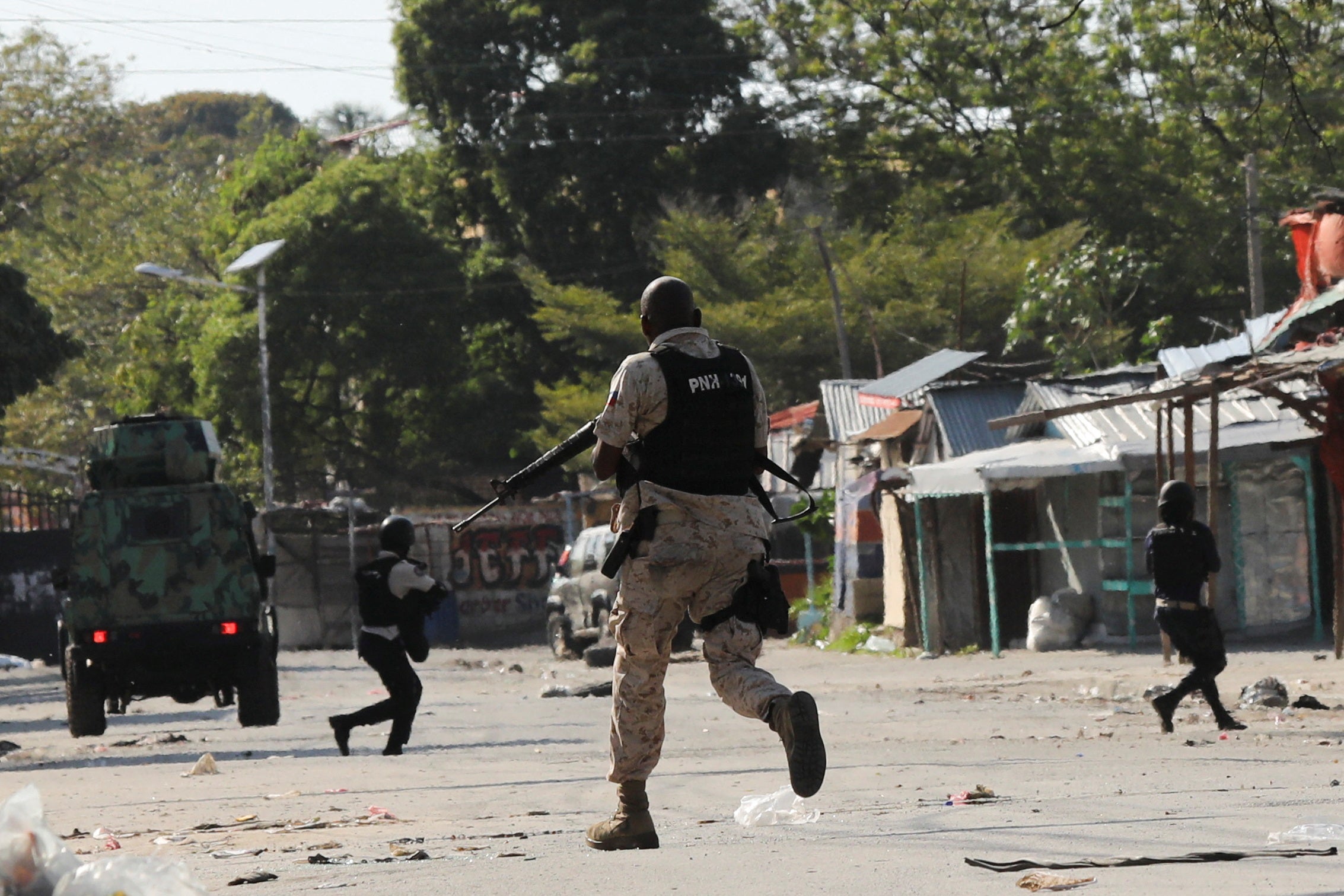 Police officers run holding their guns while confronting a gang during a protest against Prime Minister Ariel Henry's government and insecurity, in Port-au-Prince, Haiti 1 March 2024