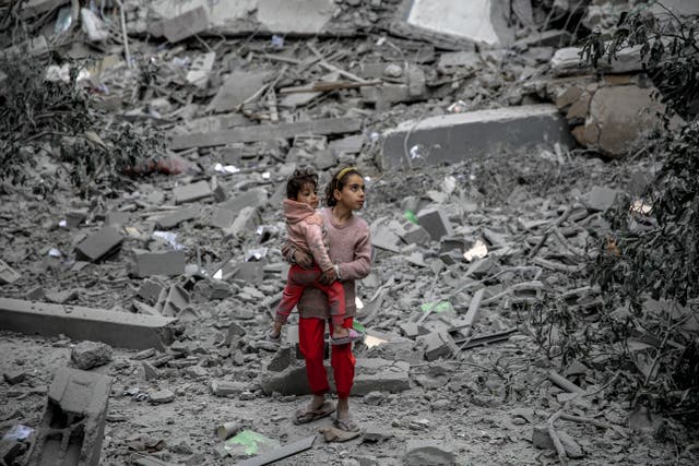 <p>A Palestinian girl carries a child through the rubble of houses destroyed by Israeli bombardment in Gaza City on March 3, 2024</p>