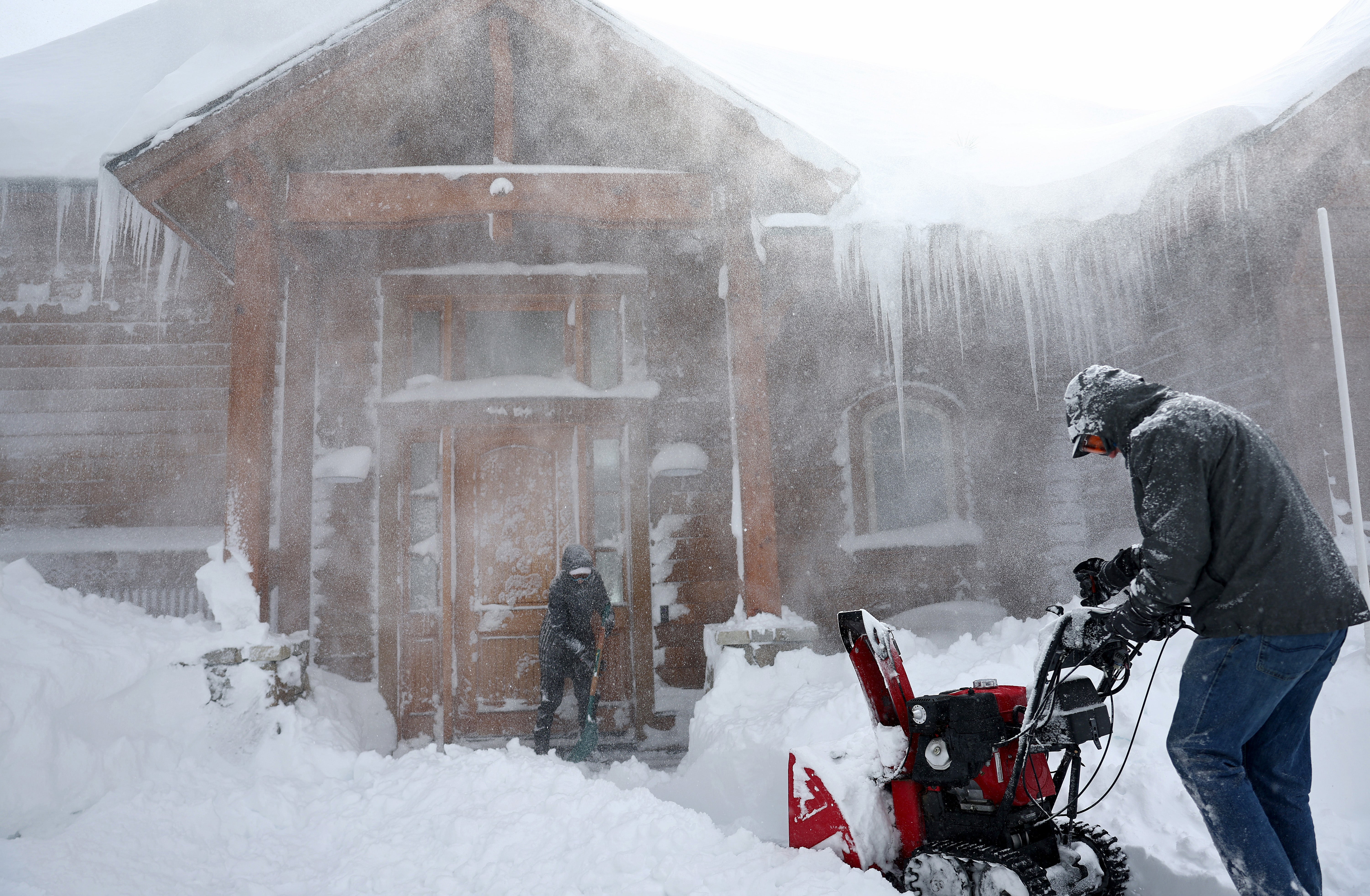 Residents clear out snow in front of their home on Donner Pass Road during a powerful multiple day winter storm in the Sierra Nevada mountains