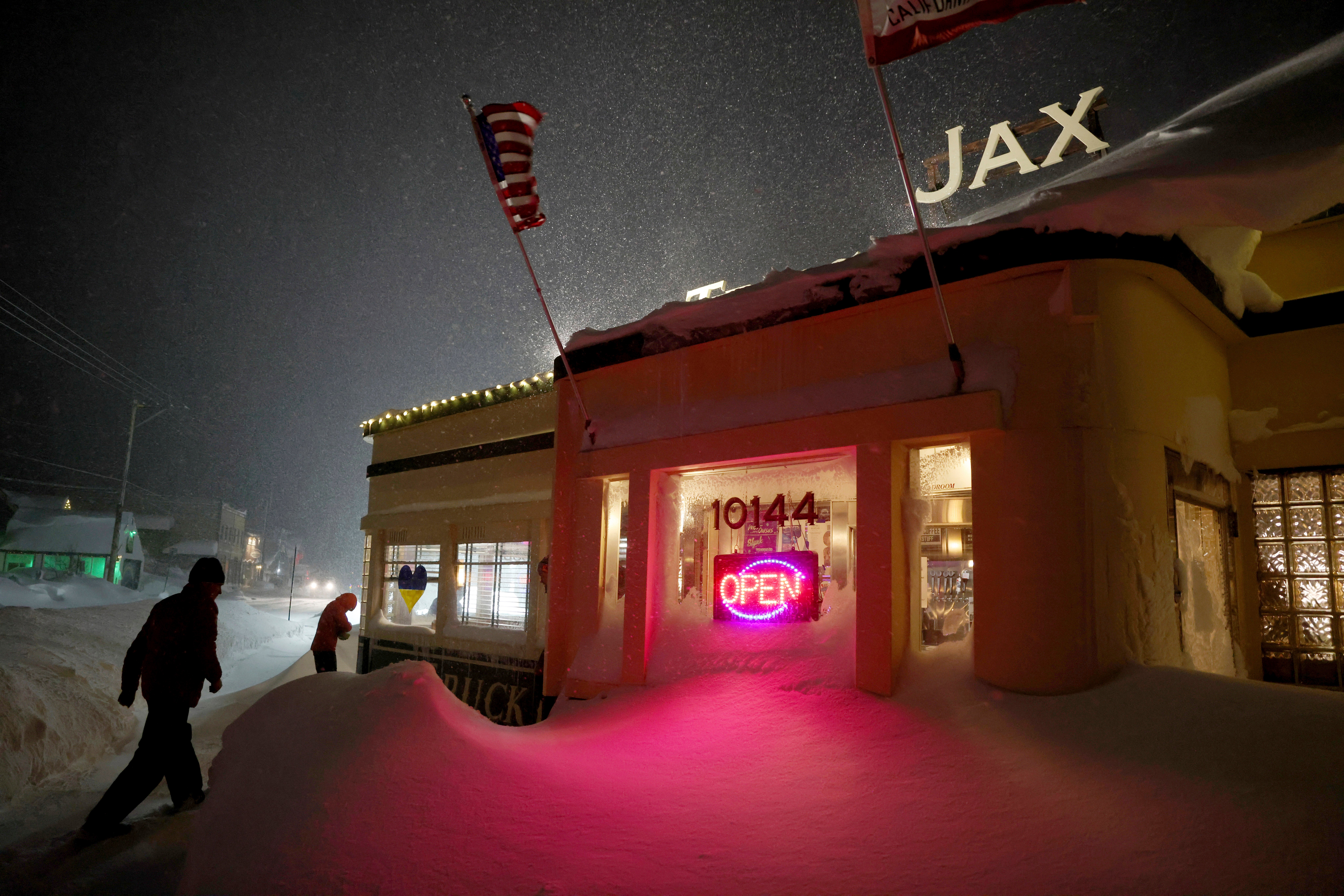 Patrons enter Jax At The Tracks diner past snow drifts in downtown Truckee, Calif., Sunday, March 3, 2024