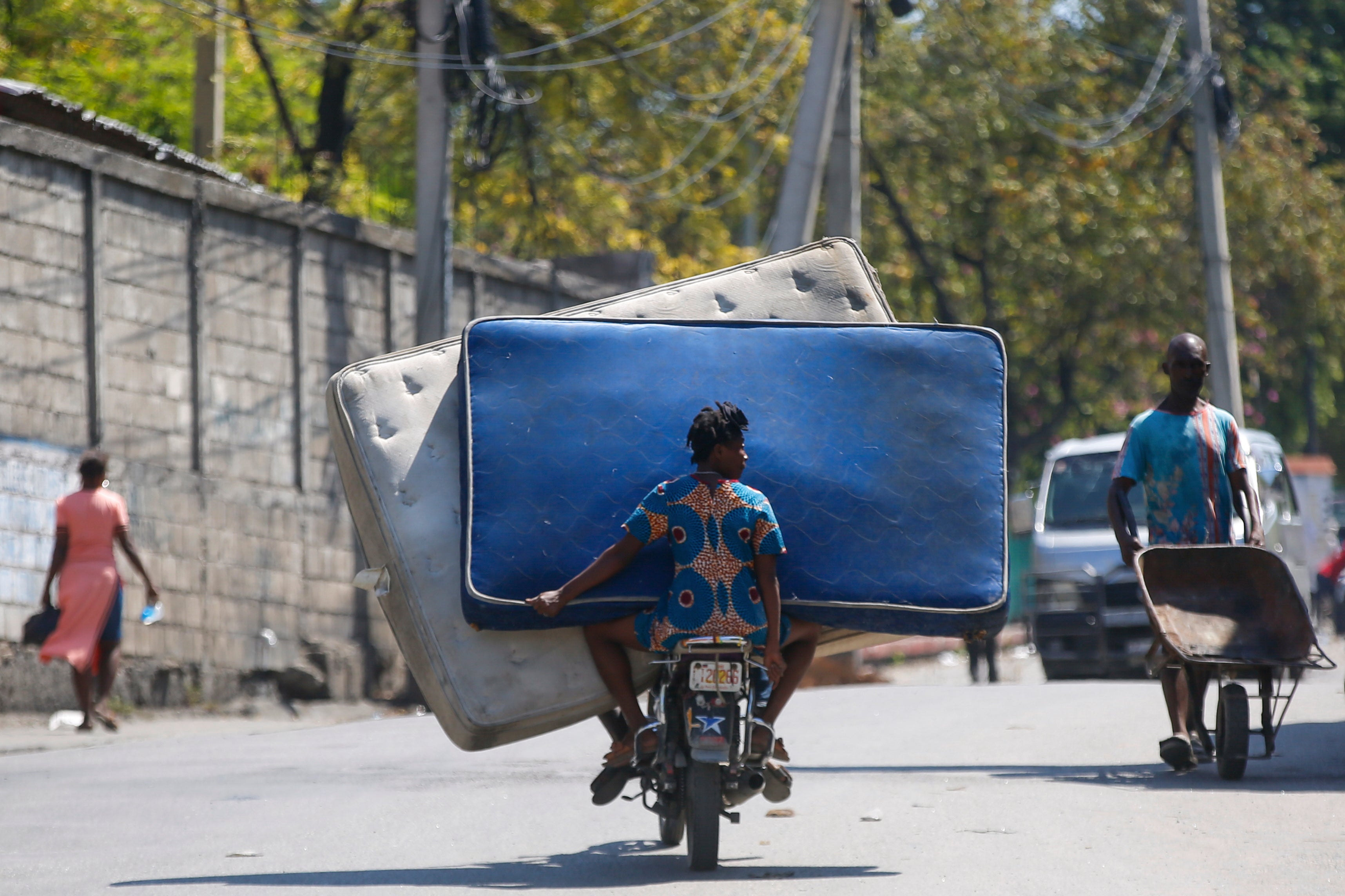 Residents transport mattresses on a motorcycle in Port-au-Prince, Haiti, Monday, March 4