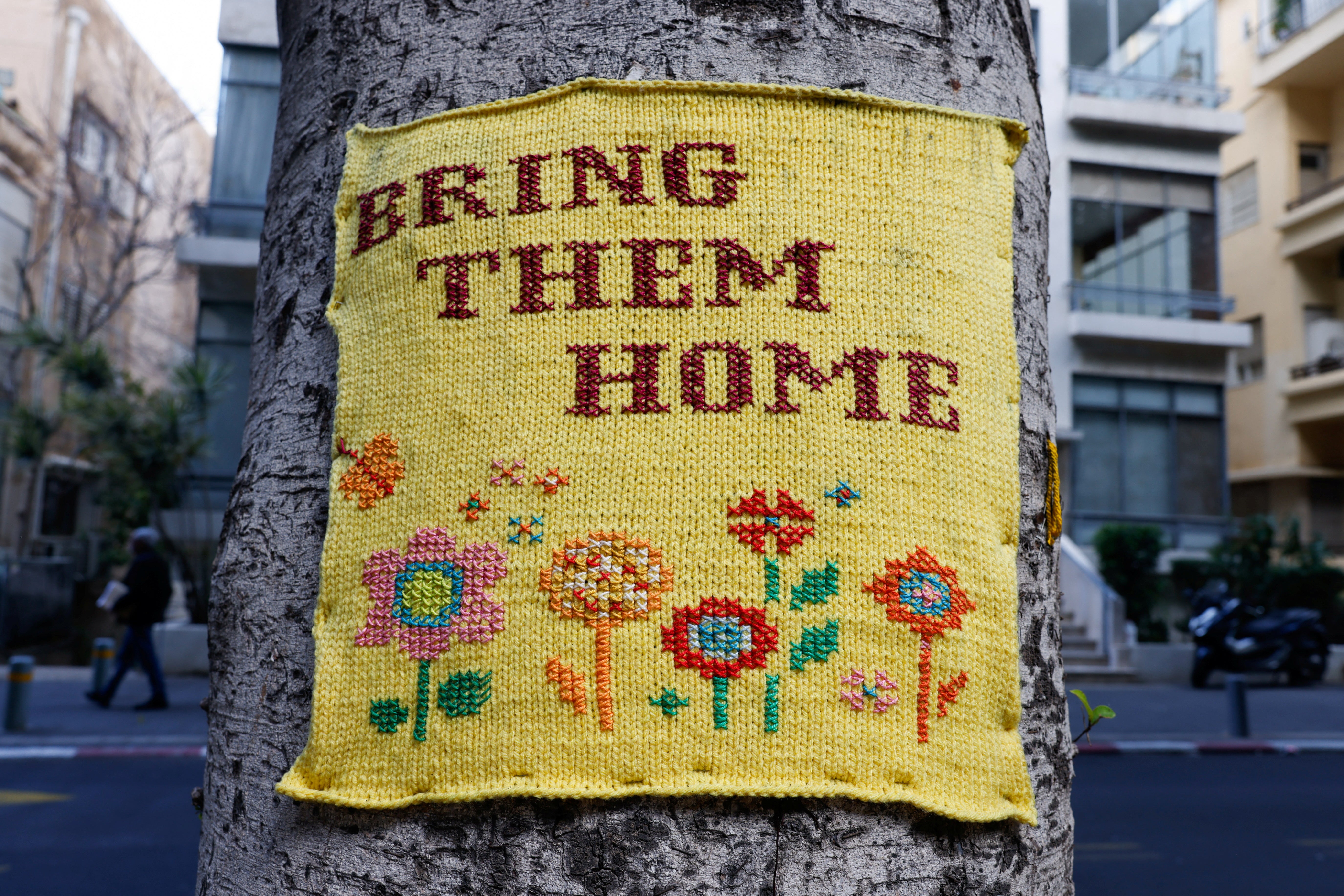 An embroidered message attached to a tree calls for the release of hostages kidnapped in the deadly 7 October attack, in Tel Aviv