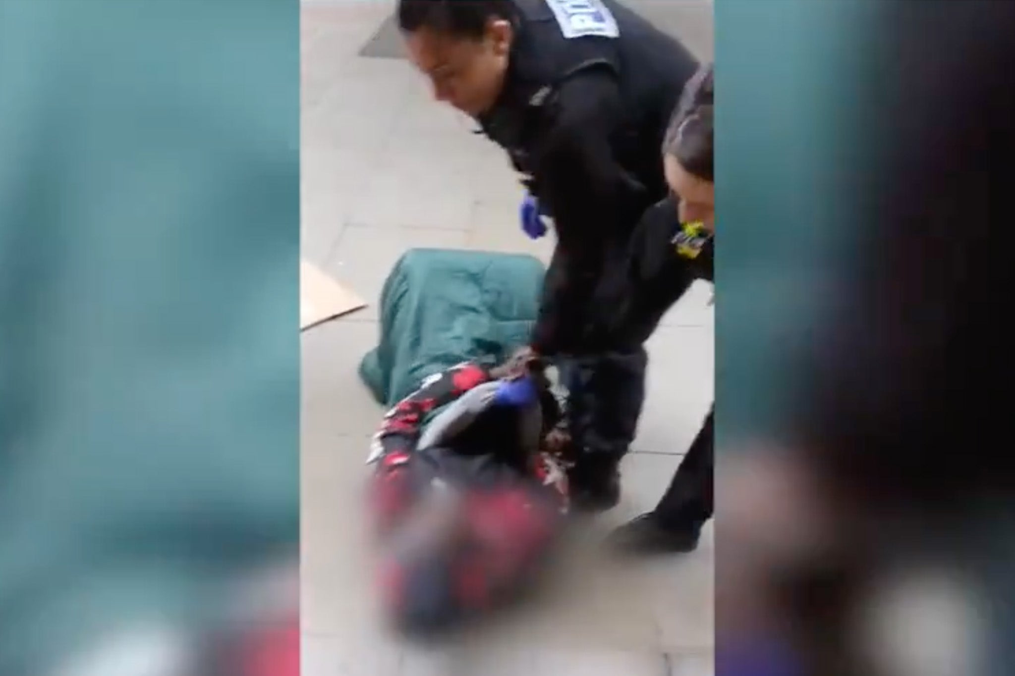 The police officer first drags the man by his sleeping bag away