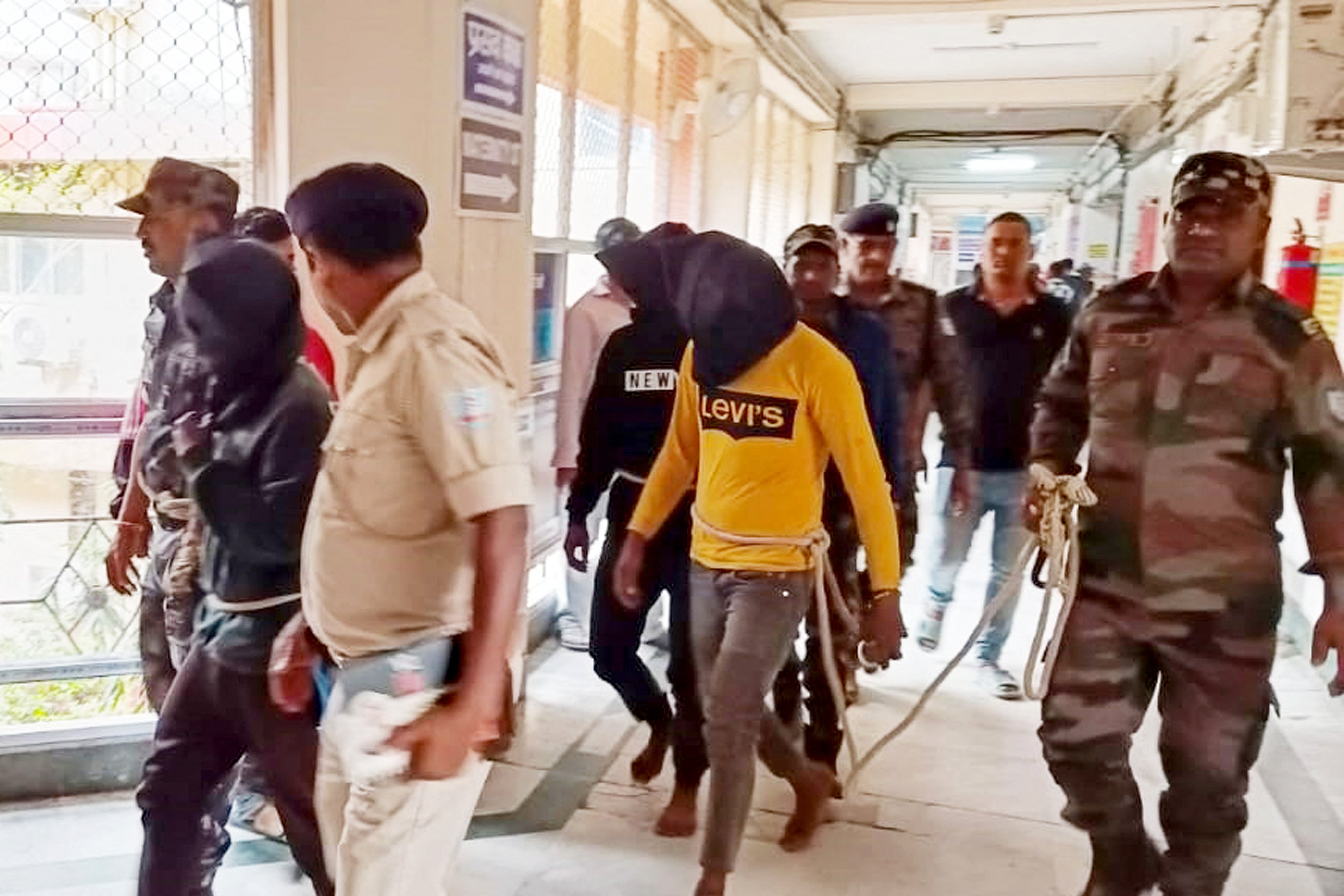 Police personnel escort men accused for allegedly carrying out a brutal assault on a Spanish woman, to a district court in Dumka, in India's Jharkhand state