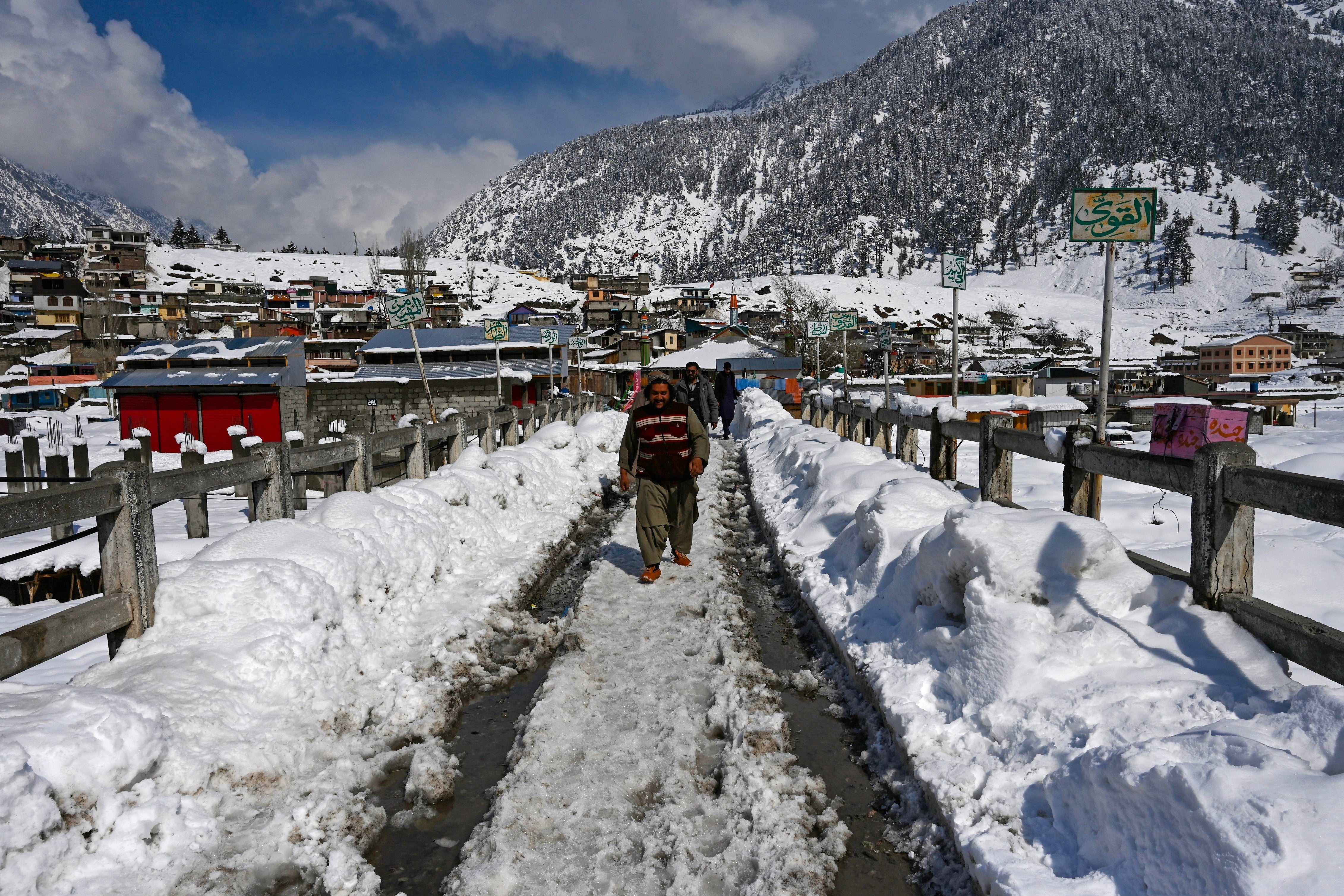 Tourists walk down a snow laden street in Kalam on 4 March 2024