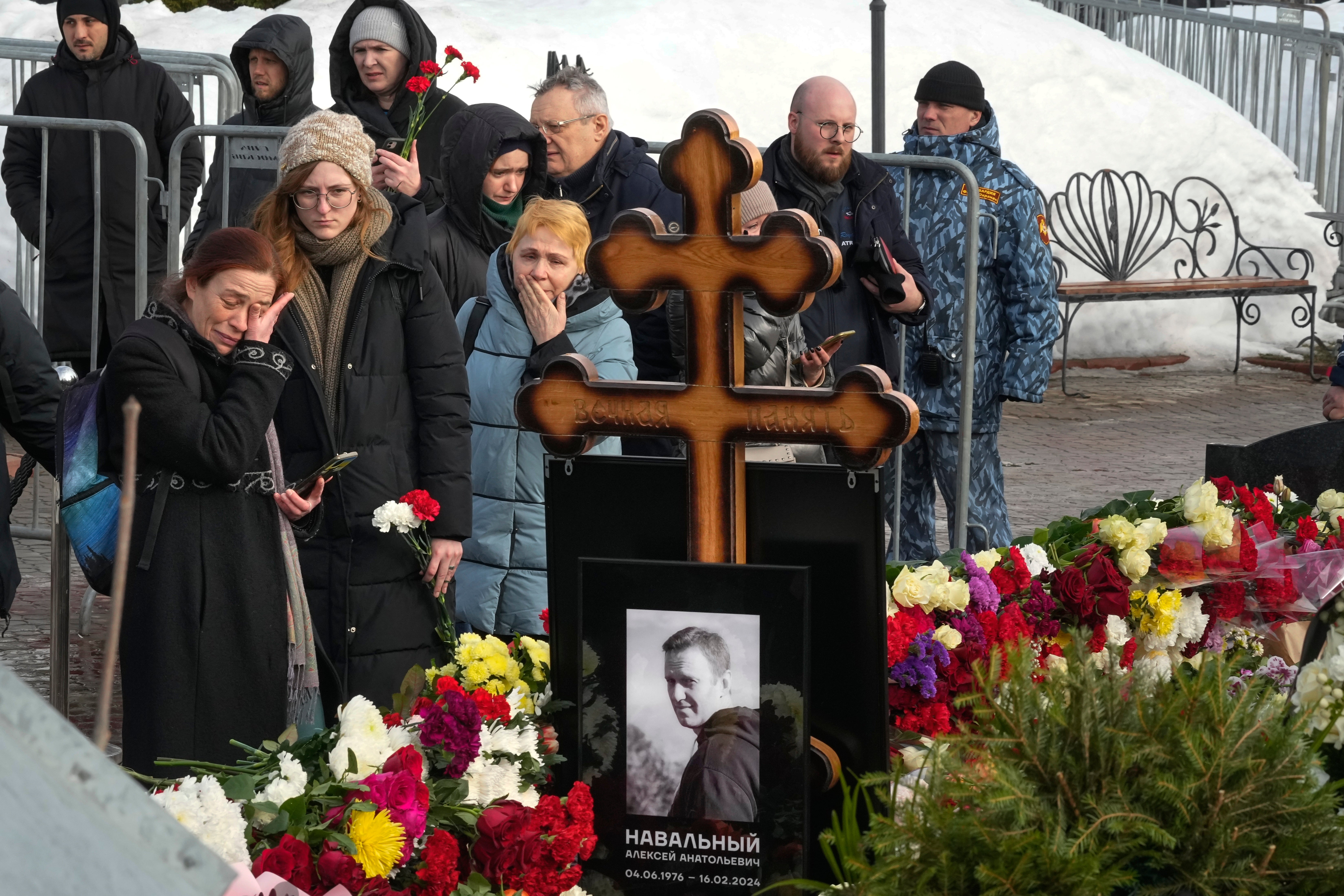 People react as they gather to lay flowers at the grave of Alexei Navalny after his funeral