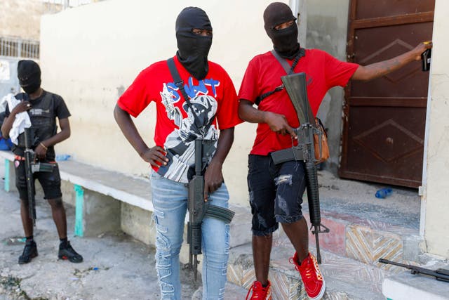 <p>Masked members of “G9 and Family” gang stand guard during a press conference by their leader Barbecue </p>