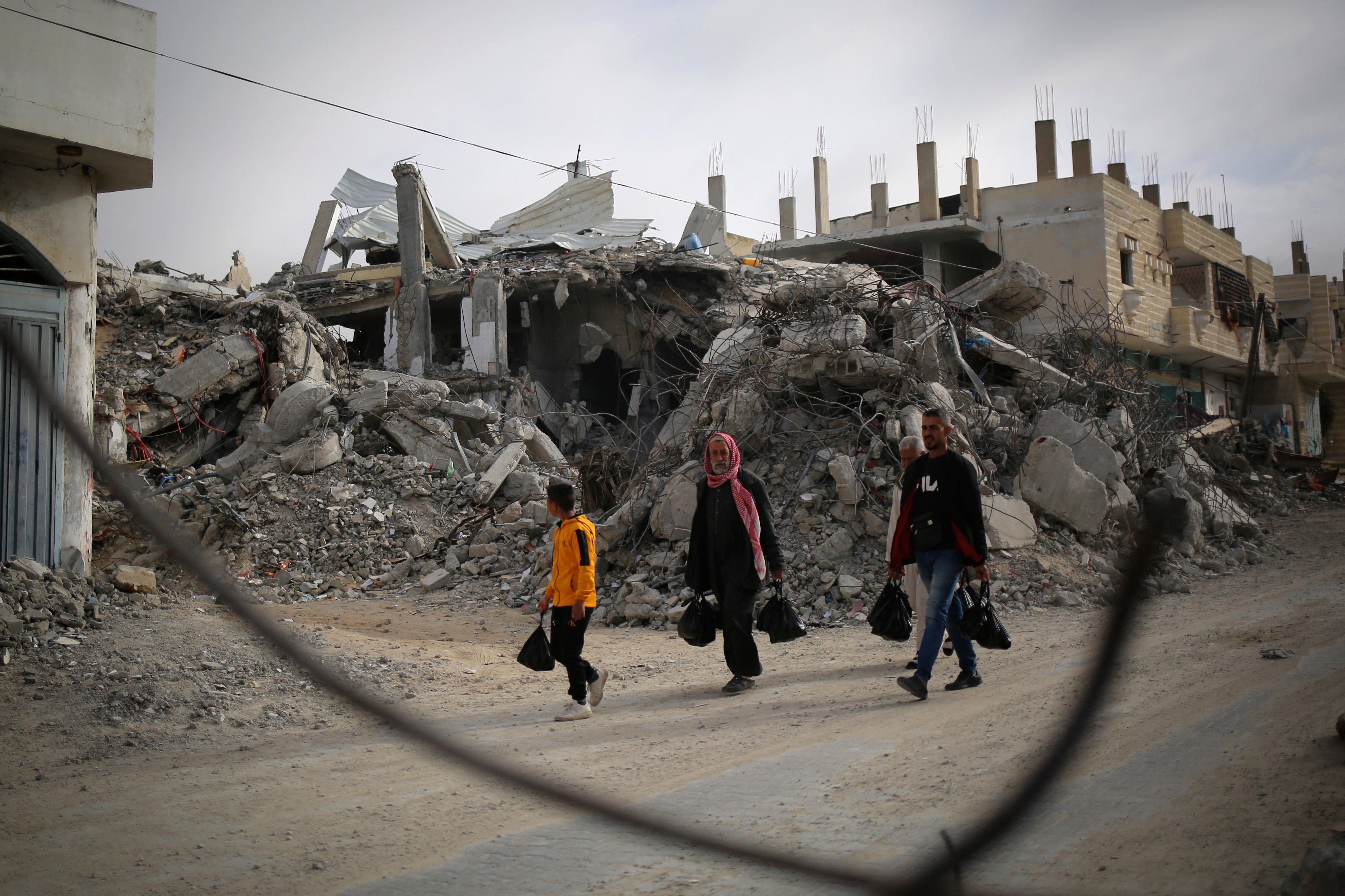 Palestinians walk past the rubble of a house destroyed by Israeli bombardment in Rafah in the southern Gaza Strip on March 3, 2024