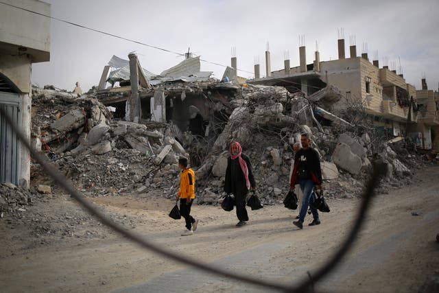 <p>Palestinians walk past the rubble of a house destroyed by Israeli bombardment in Rafah in the southern Gaza Strip on 3 March 2024</p>