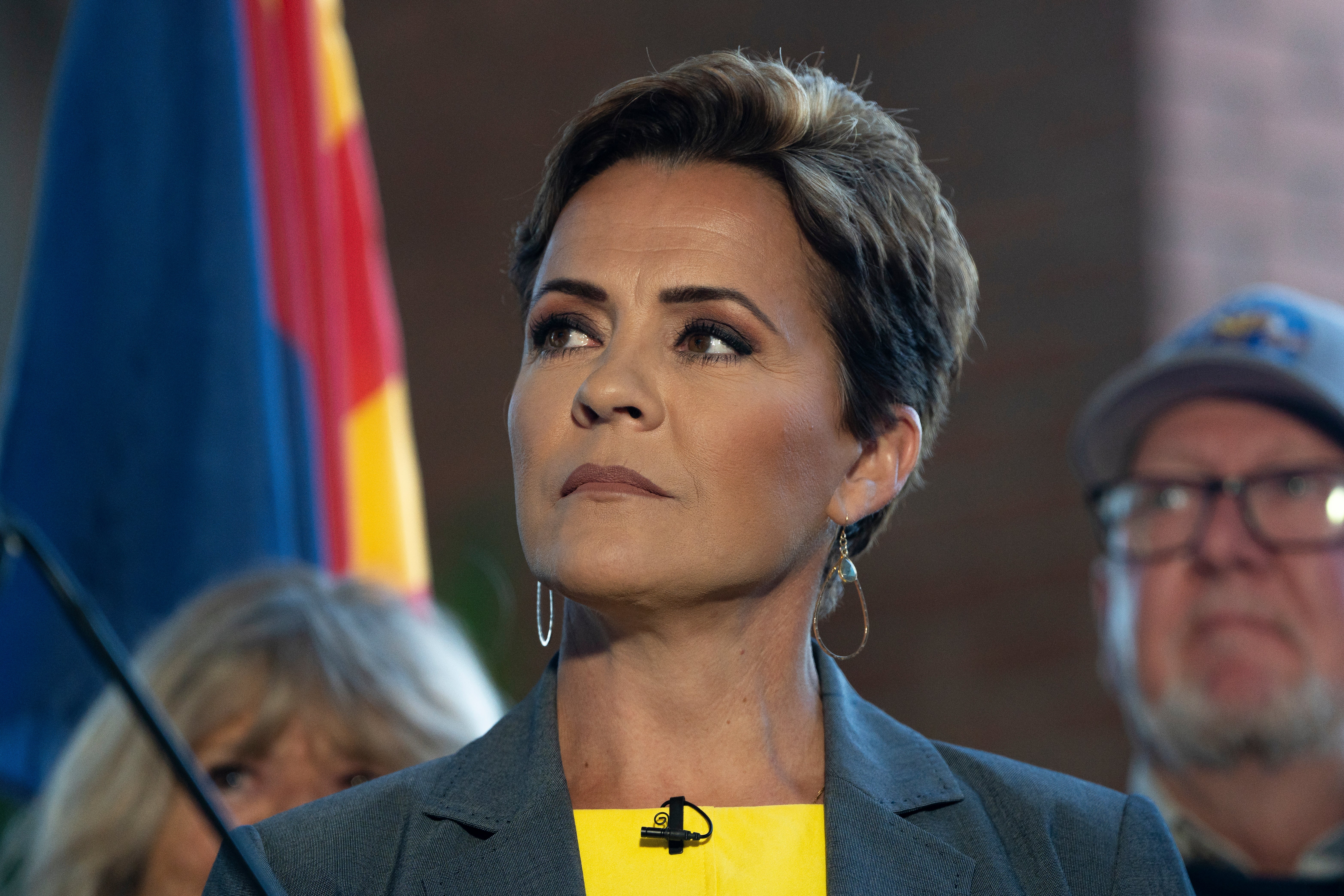 Kari Lake listens as John Barrasso speaks at a news conference in Phoenix, Arizona