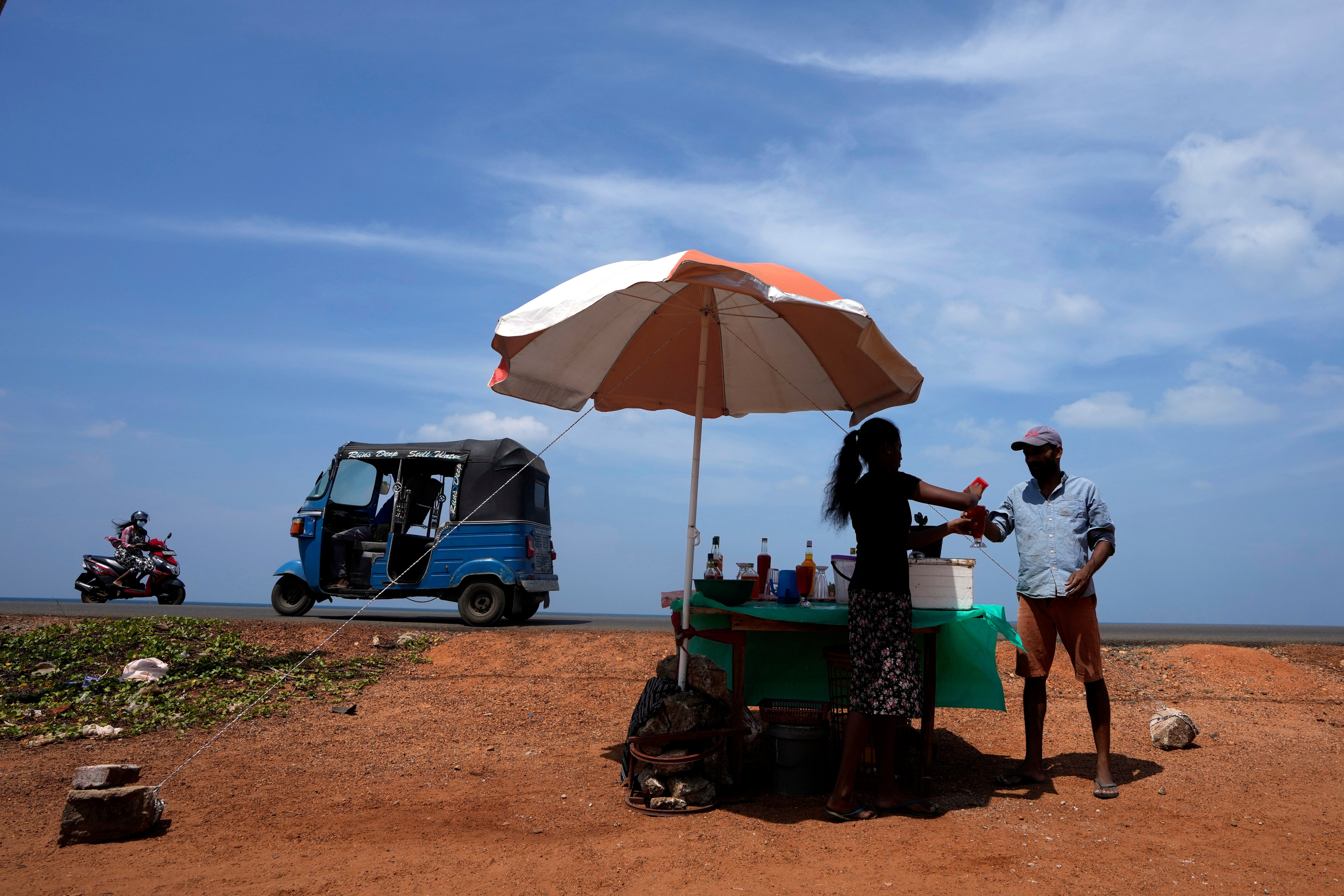 FILE - A man buys a cool drink from a roadside vendor on a sunny day in Mahawewa, a village north of Colombo