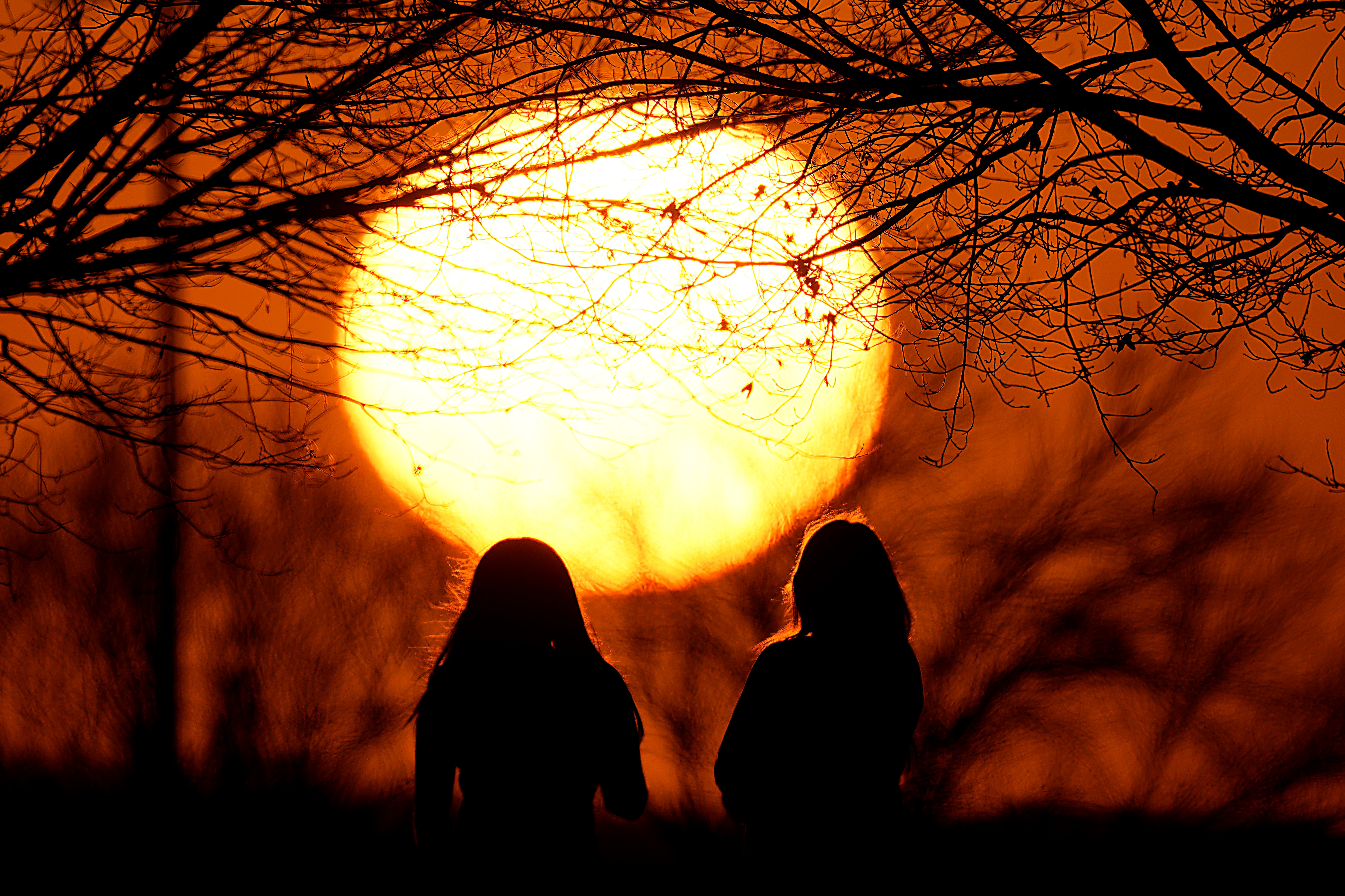People watch the sunset at a park on an unseasonably warm day in Kansas City