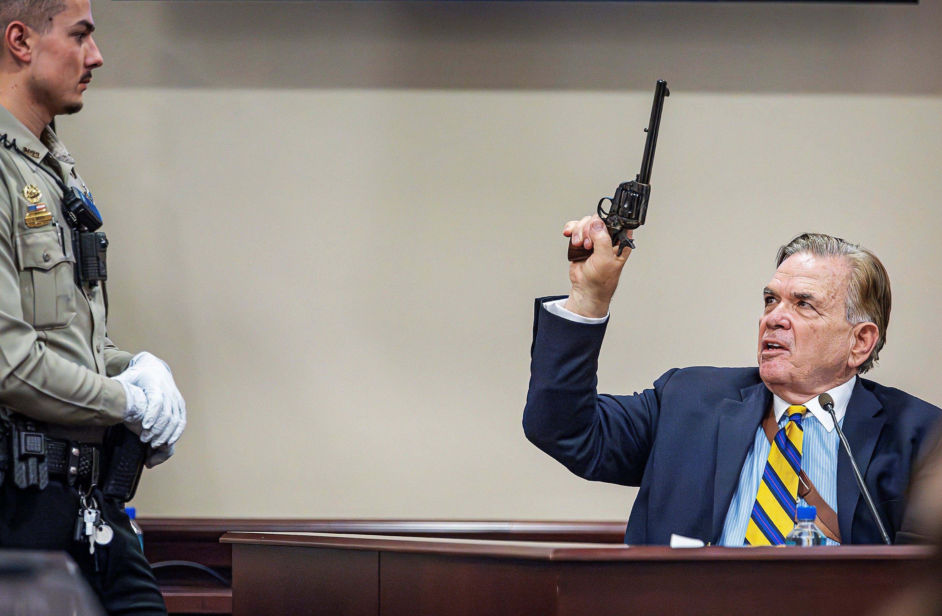 Santa Fe County Deputy Levi Abeyta, left, watches as expert witness for the defense Frank Koucky III demonstrates how to uncock a gun like the one used on the set of the movie ‘Rust’