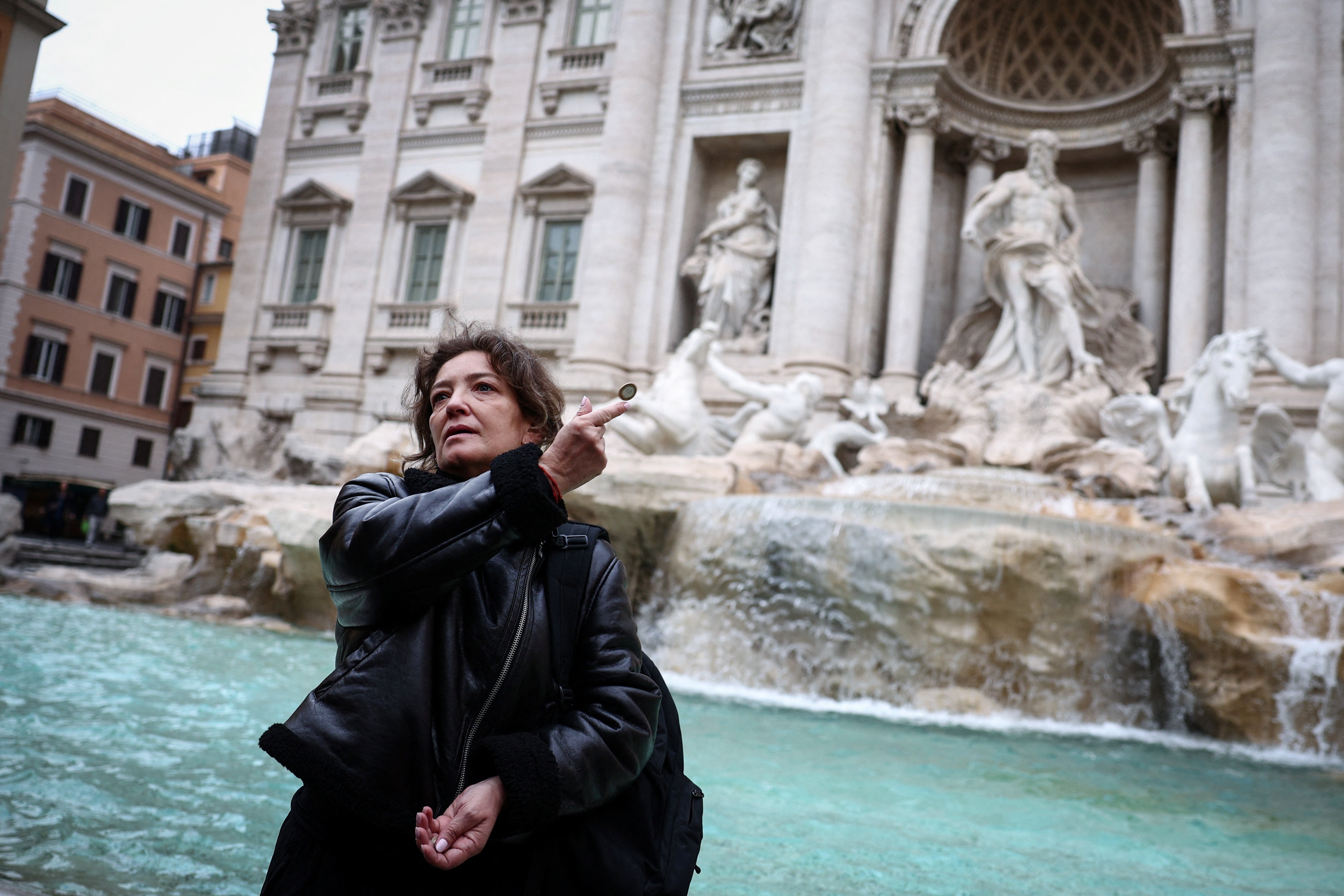 Carola, from Chile, throws a coin into the Trevi Fountain in Rome, Italy