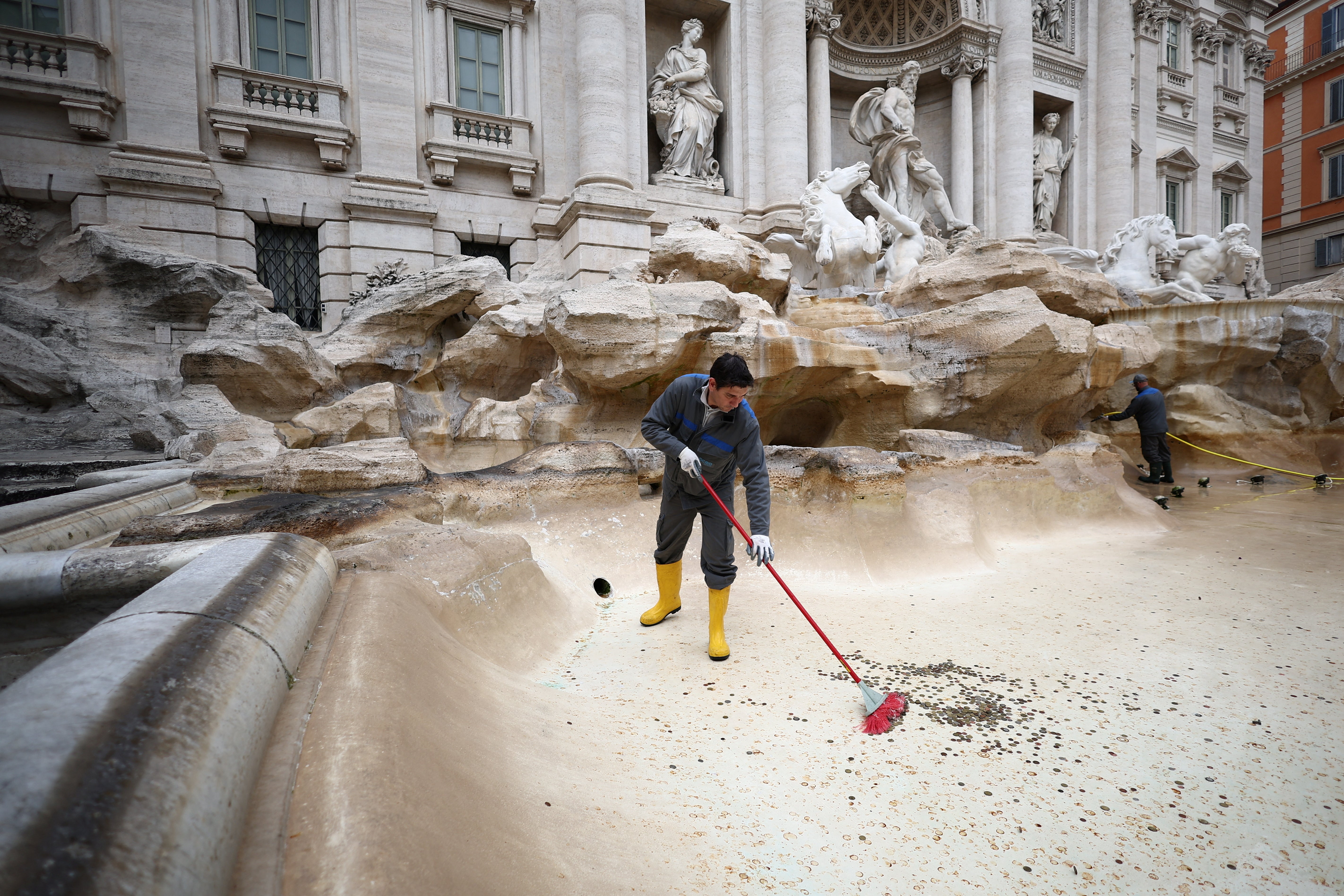 ACEA utility worker Alexio Cola uses a broom to gather coins to be collected in the emptied Trevi Fountain in Rome