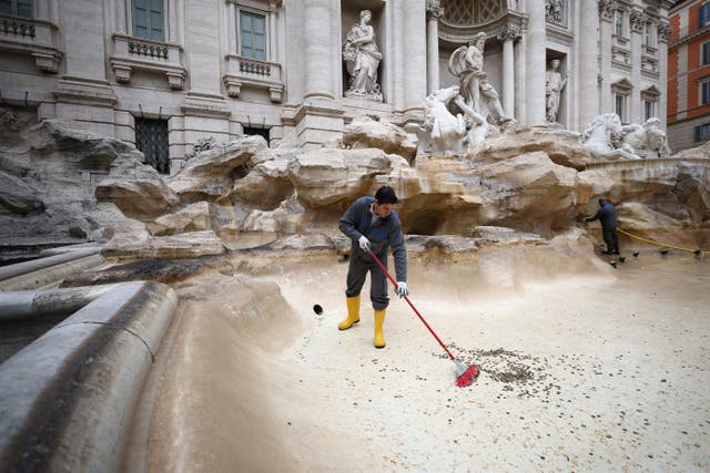 <p>ACEA utility worker Alexio Cola uses a broom to gather coins to be collected in the emptied Trevi Fountain in Rome</p>