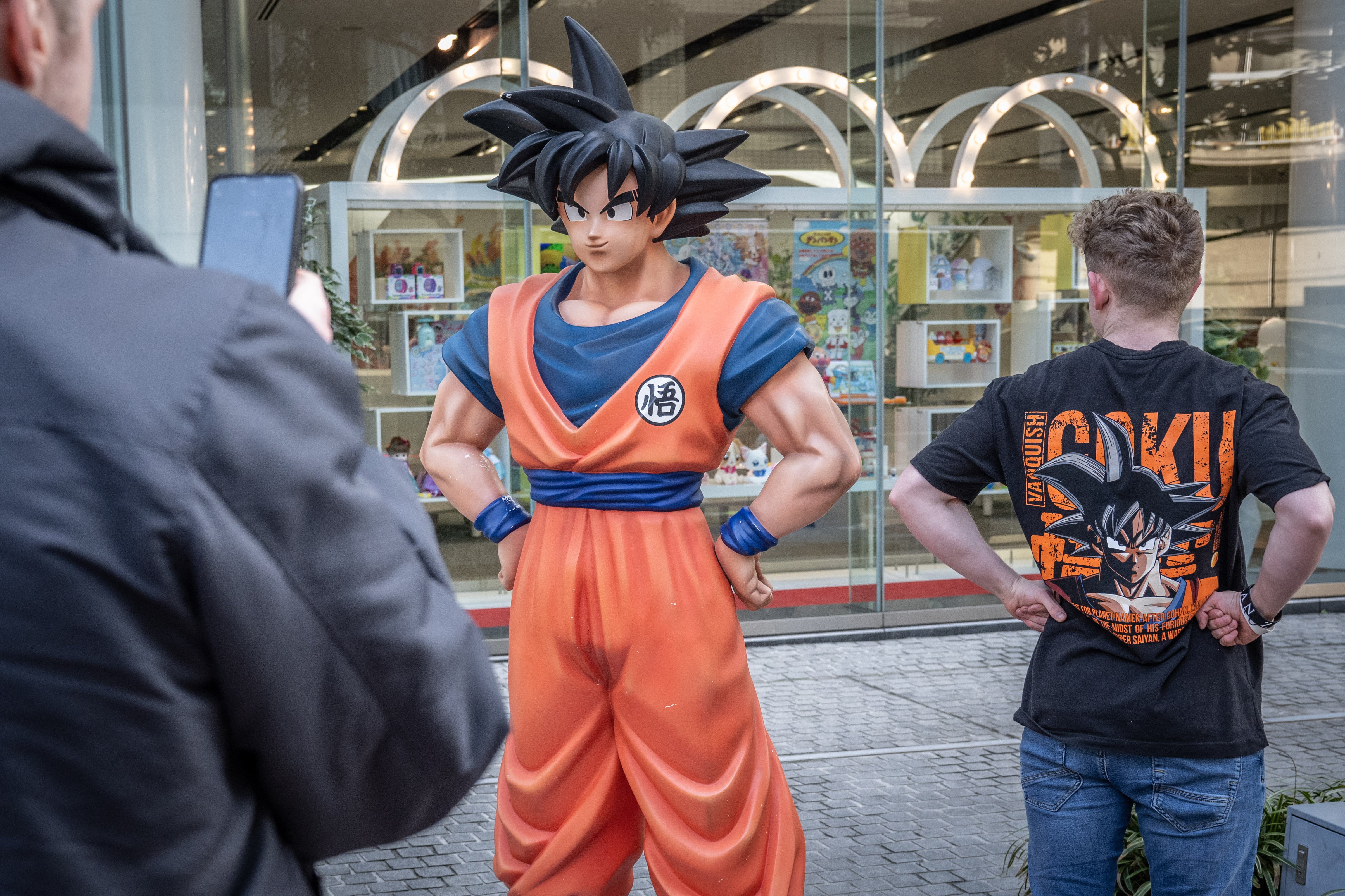 A tourist wearing a T-shirt of Dragon Ball has his photographs taken with a statue of Dragon Ball character ‘Son Goku’