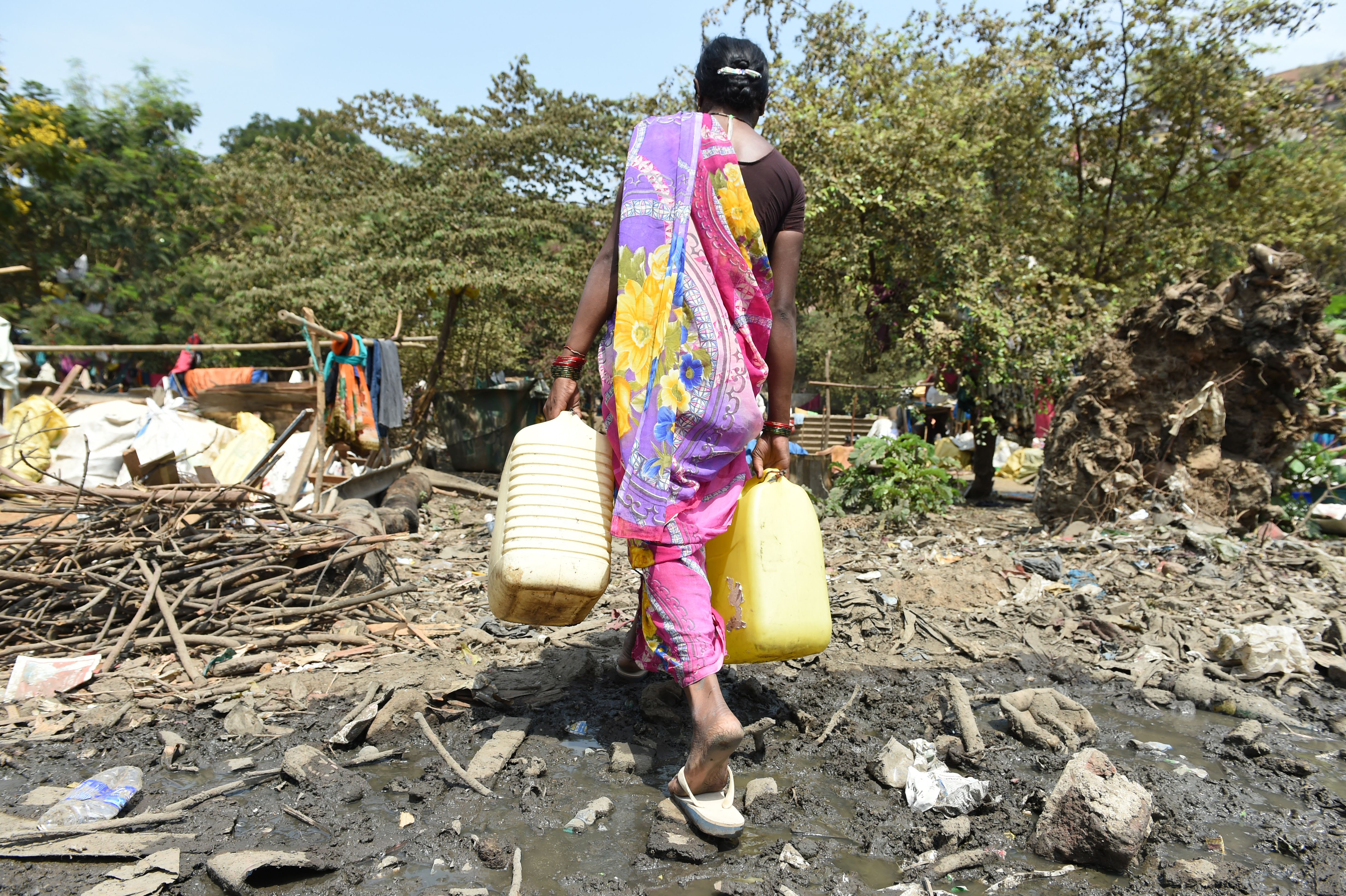 File photo: A woman carries containers filled with drinking water in Maharashtra. Frequent droughts in the region are forcing people to leave their farms and work as labourers under unfair contracts