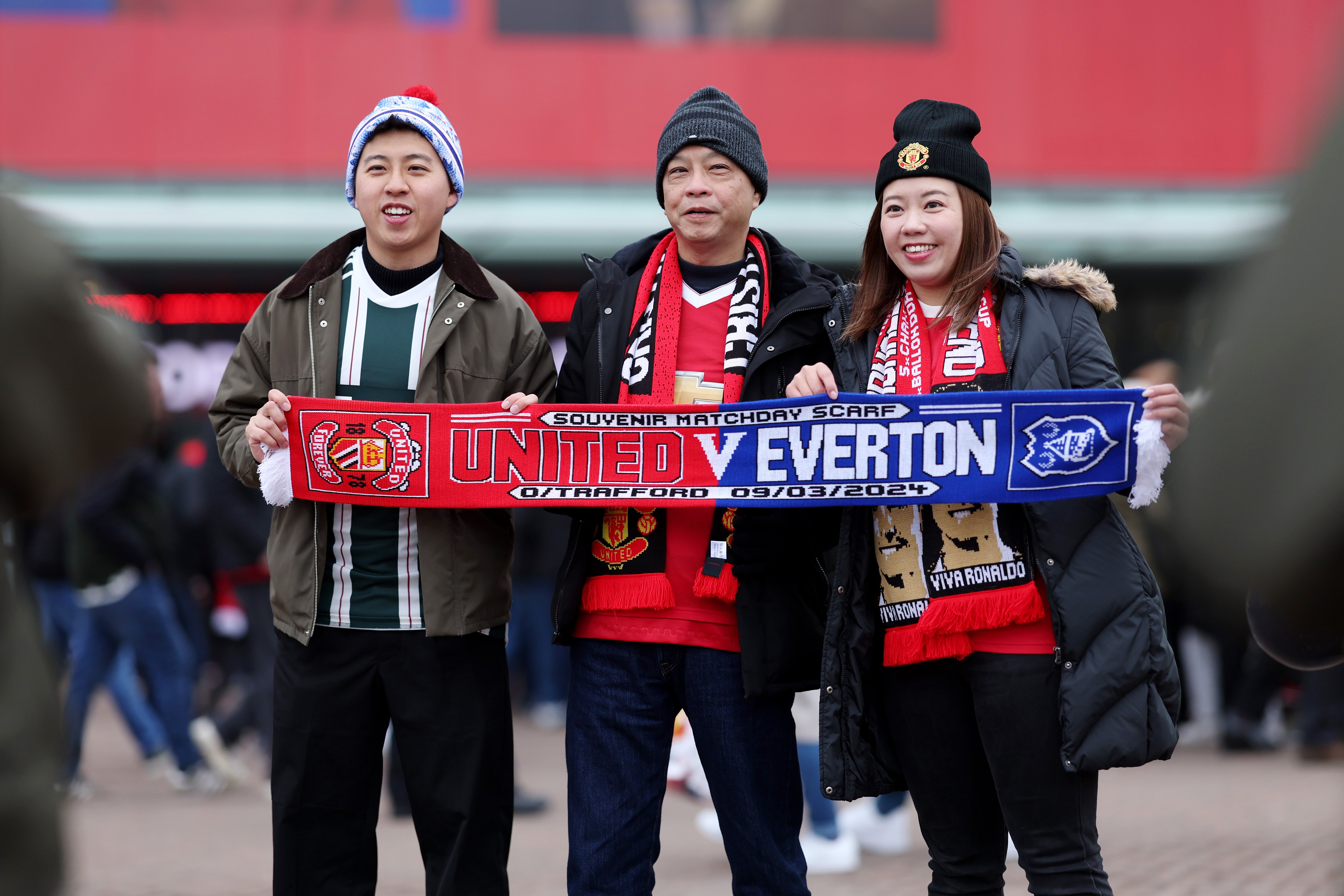 Fans outside Old Trafford pose with a half-and-half scarf