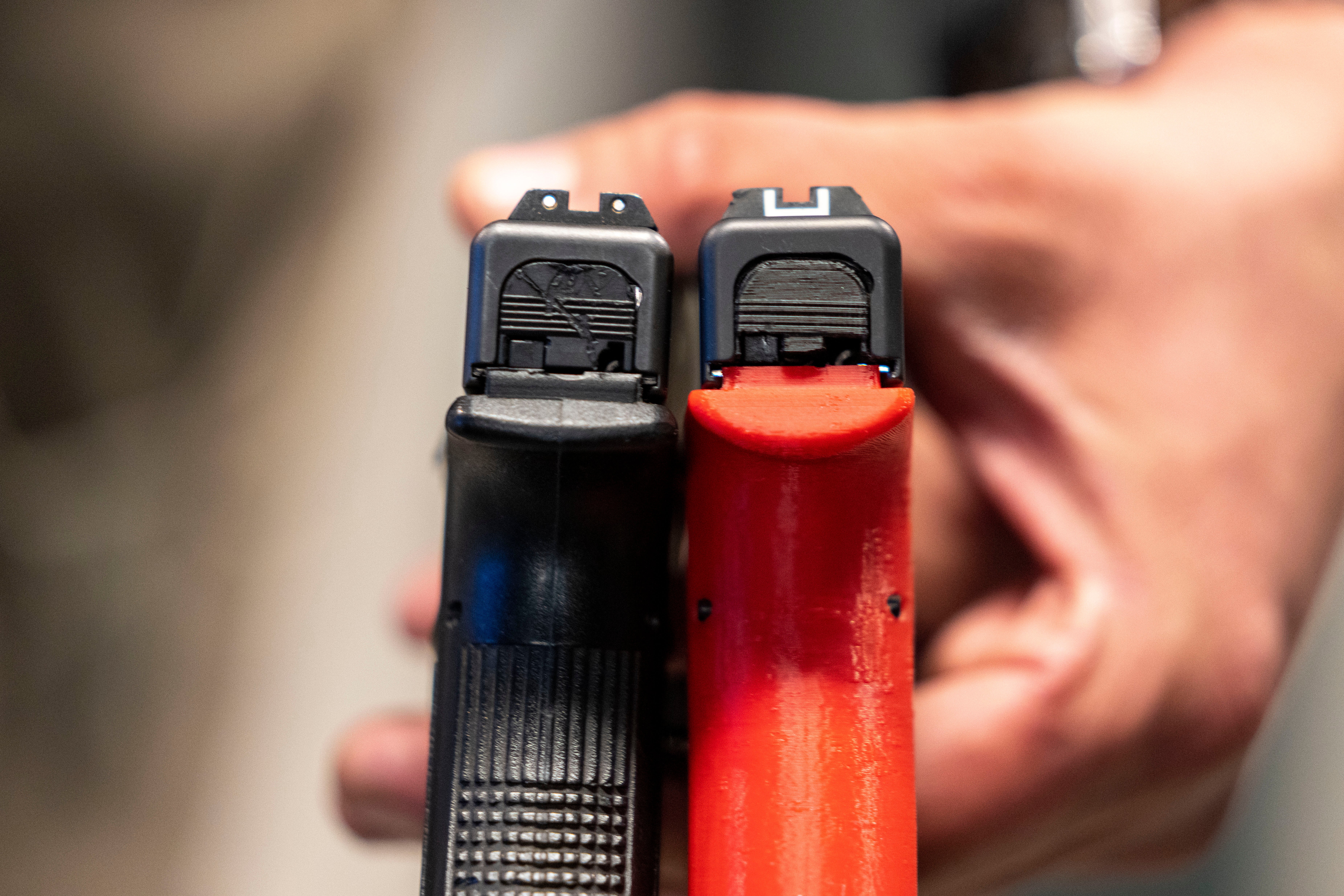 Two semi-automatic pistols are displayed for a photograph, one with a conversion device installed