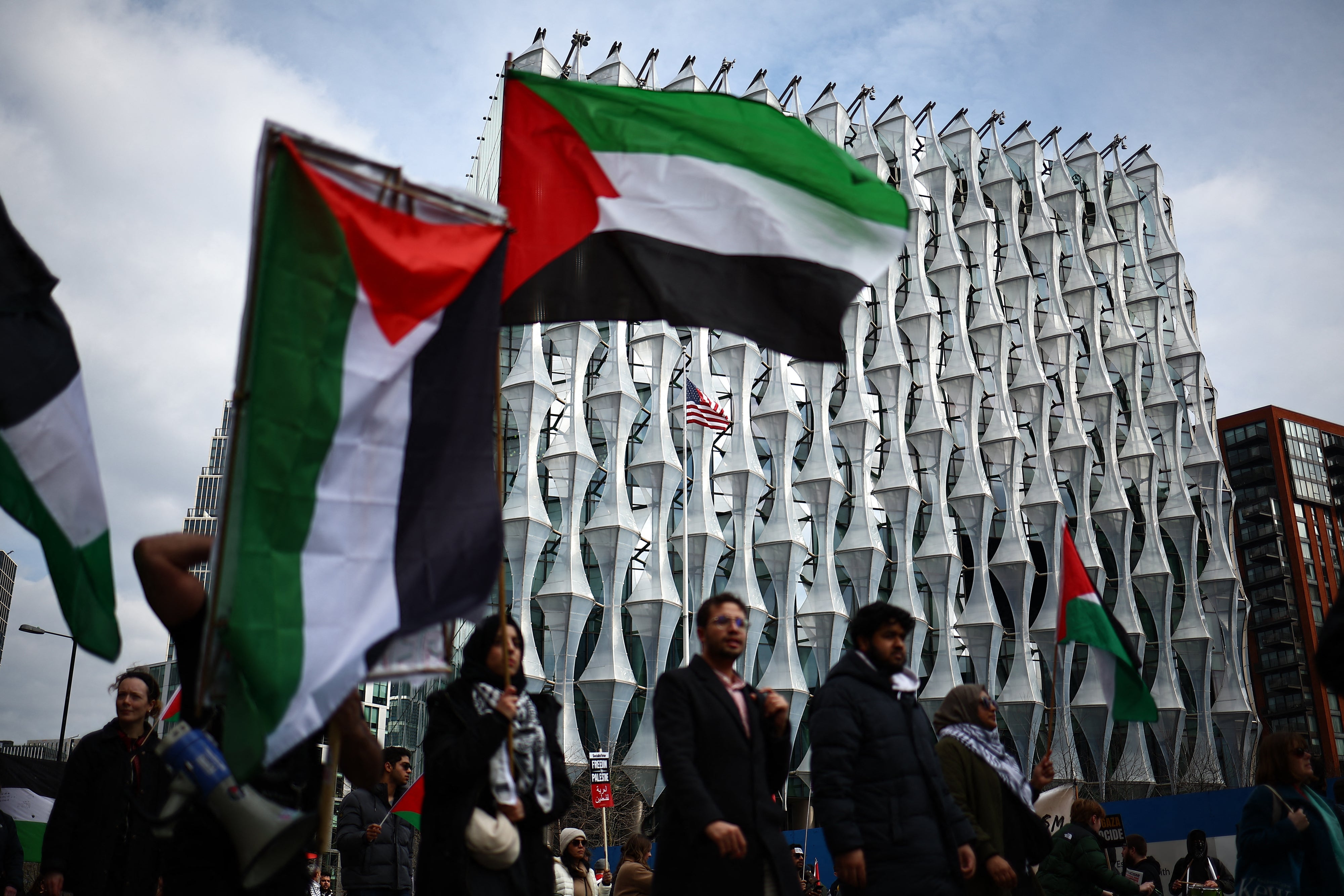 Pro-Palestinian activists and supporters wave flags and carry placards on a march past the US Embassy