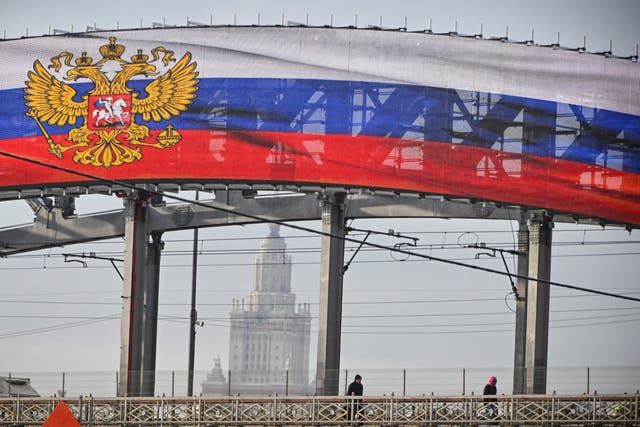 <p>A mediascreen set up on a railway bridge displays the Russian State Emblem and the national tricolor flag in western Moscow on February 14, 2024, in front of the main building of the Moscow State University</p>