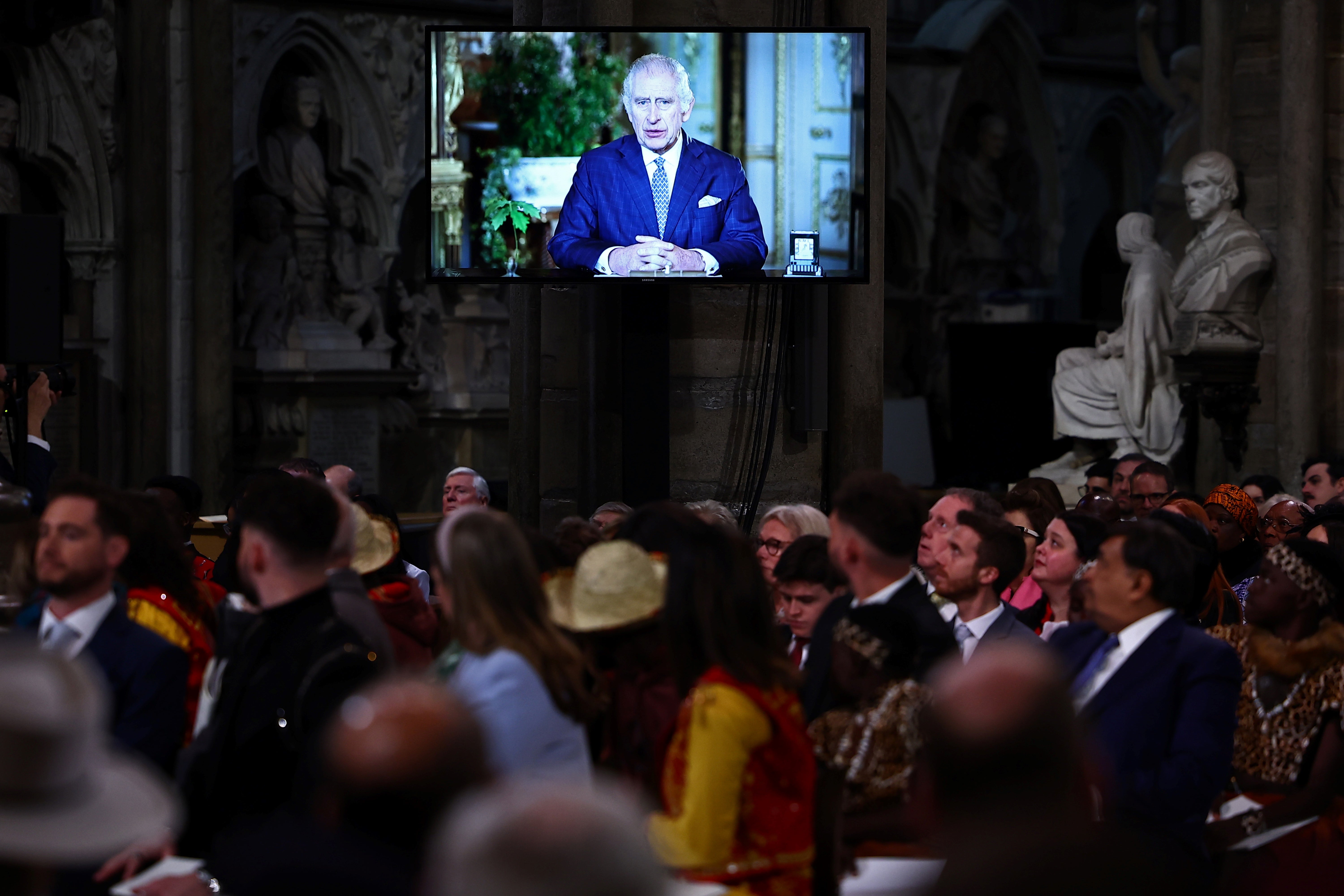 Guests watch a video of King Charles delivering a message during the annual Commonwealth Day Service at Westminster Abbey in London on Monday