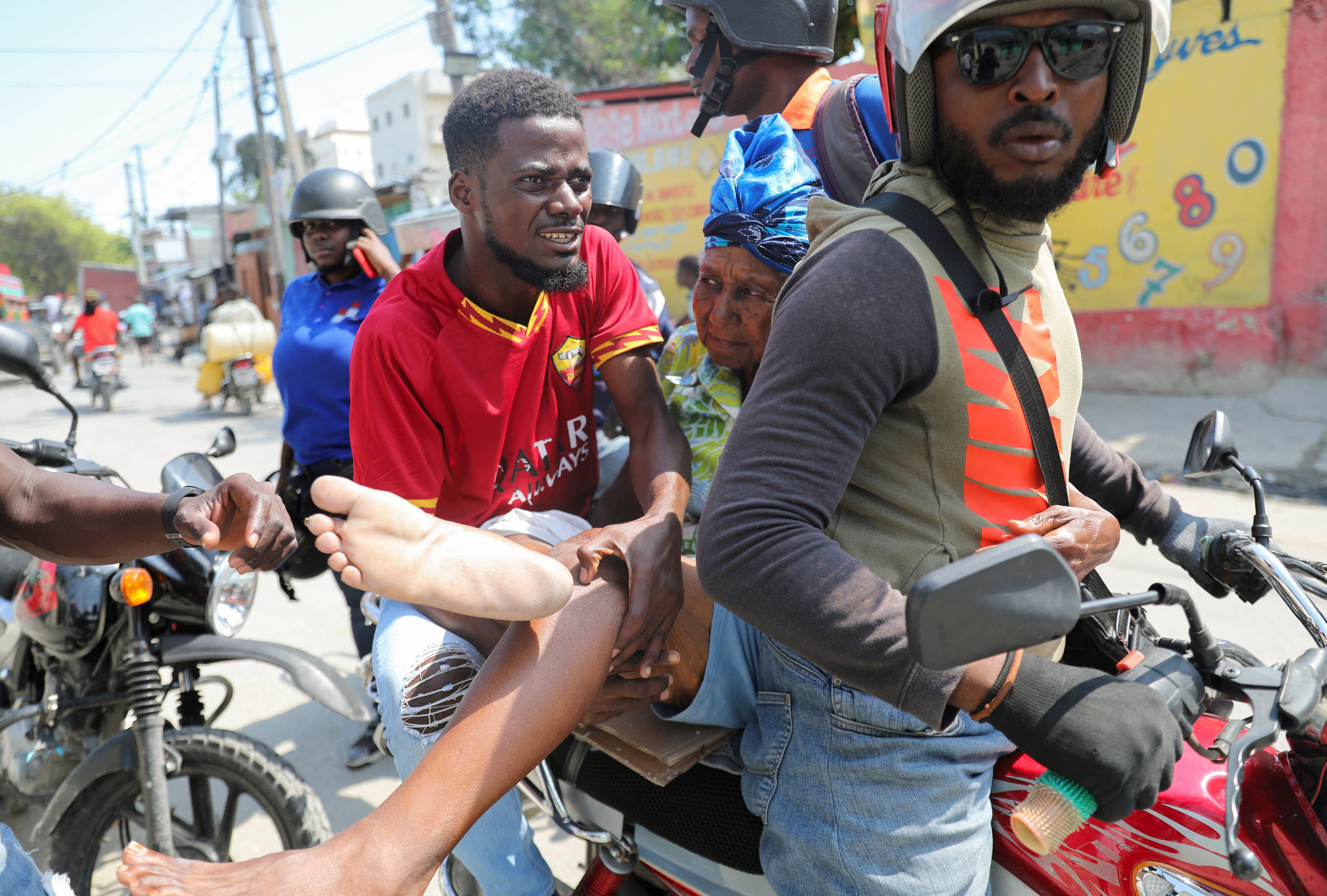 A woman with a gunshot wound is transported on a motorcycle in Port-au-Prince