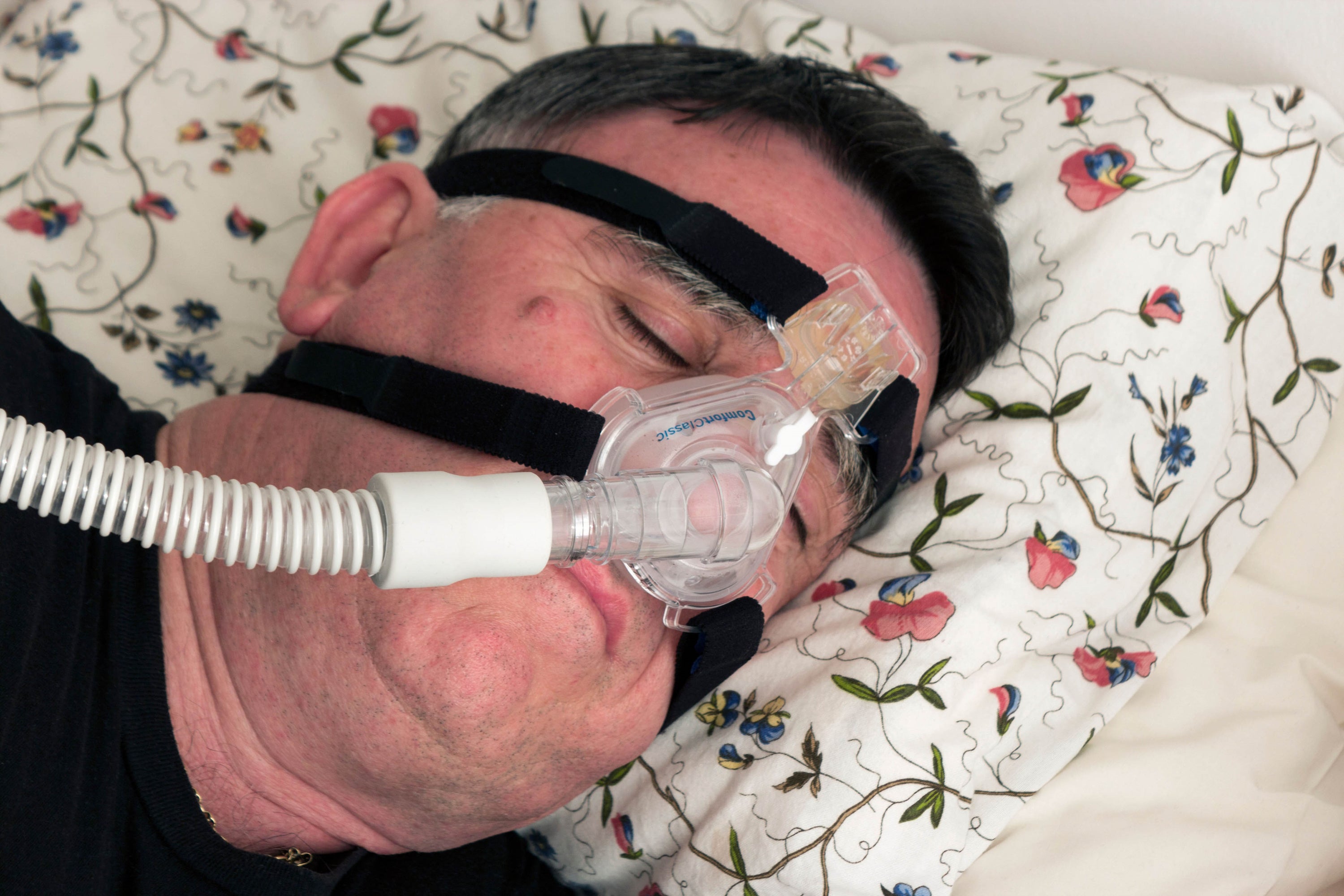 A man using a CPAP face mask and machine used for the treatment of sleep apnoea