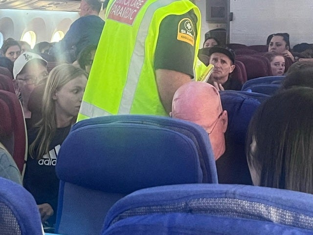 A paramedic walks onboard as passengers look on, after an incident on a LATAM Airlines Boeing 787, in Auckland