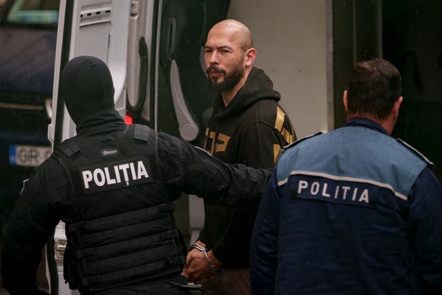 <p>Police officers escort Andrew Tate, center, handcuffed, to the Court of Appeal in Bucharest, Romania, Tuesday, March 12</p>