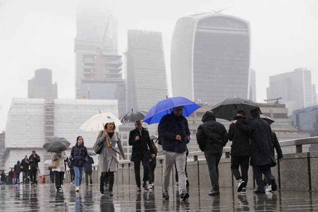 <p>People walk in the rain over London Bridge on Tuesday  </p>