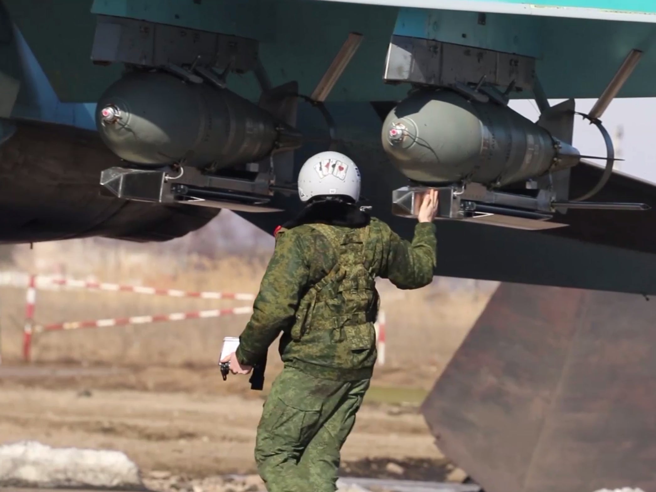 A Russian pilot inspects FAB bombs mounted by a Russian Su-34 fighter jet