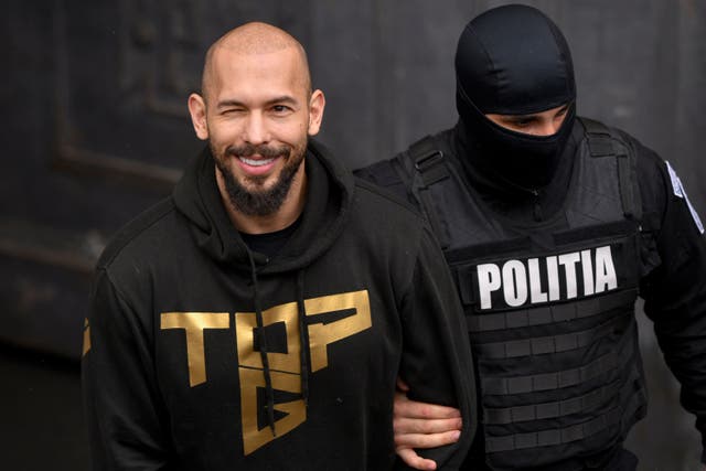 A police officer escorts Andrew Tate from the Court of Appeal in Bucharest, Romania (AP Photo/ Alexandru Dobre)